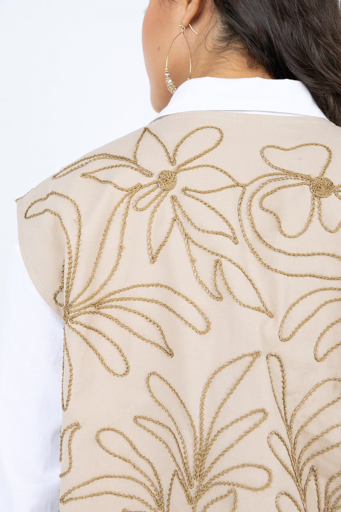 Beige embroidered vest with gold floral patterns on a white background