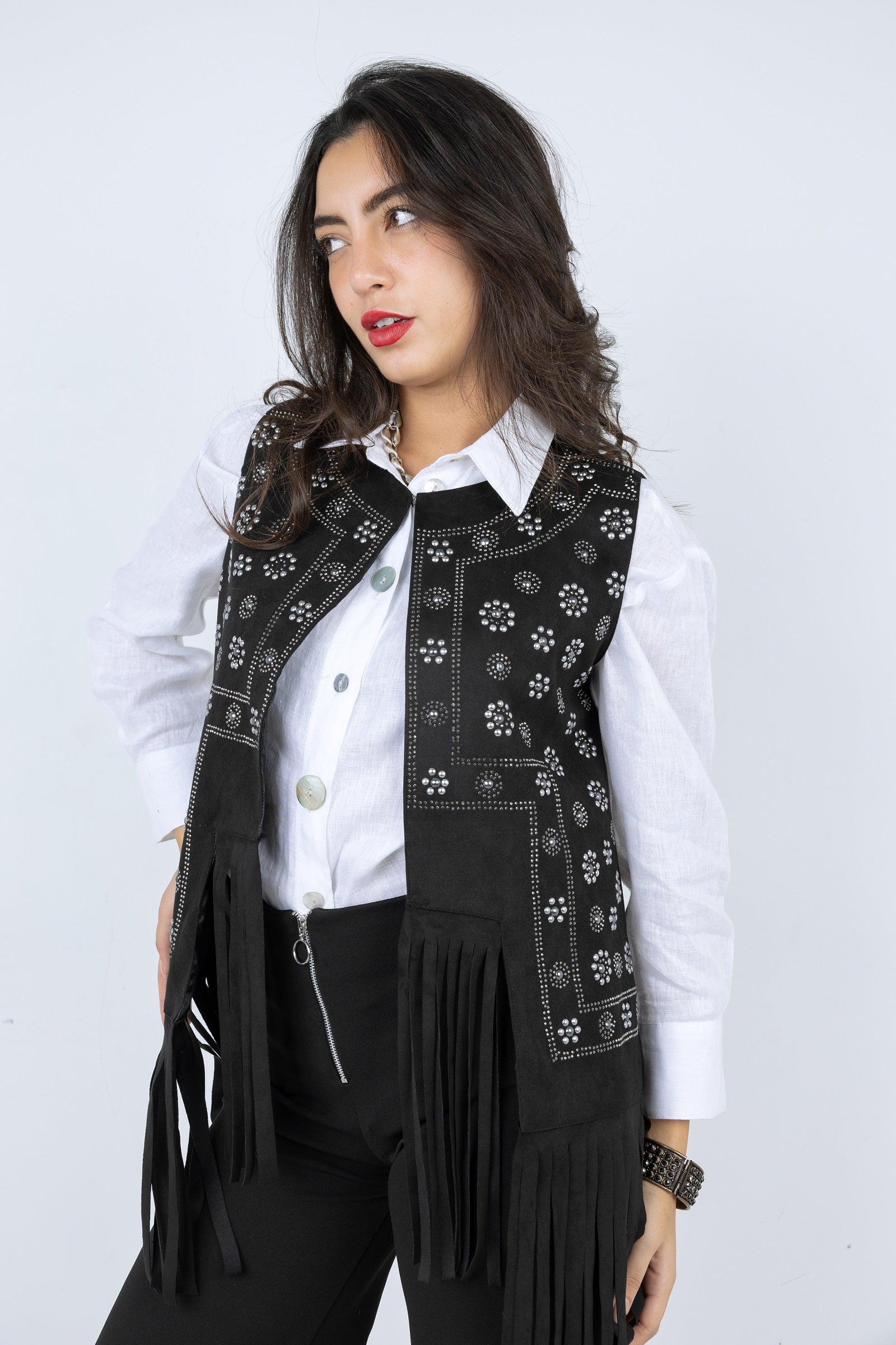 Woman wearing a black embroidered vest with fringe on a white background