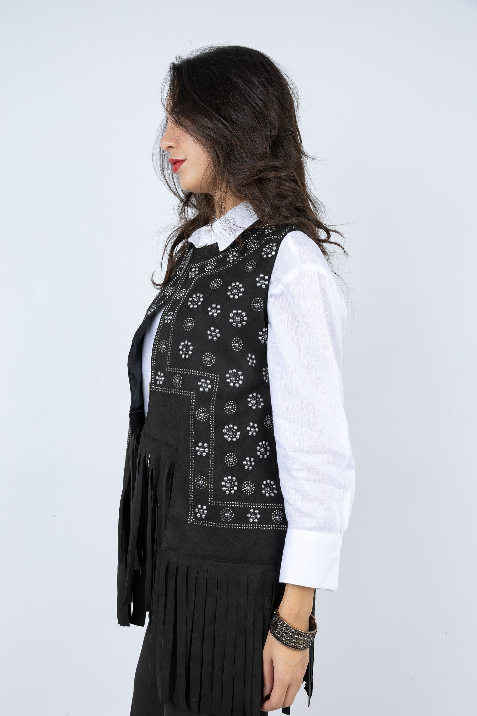 Woman wearing a black embroidered vest over a white shirt on a white background