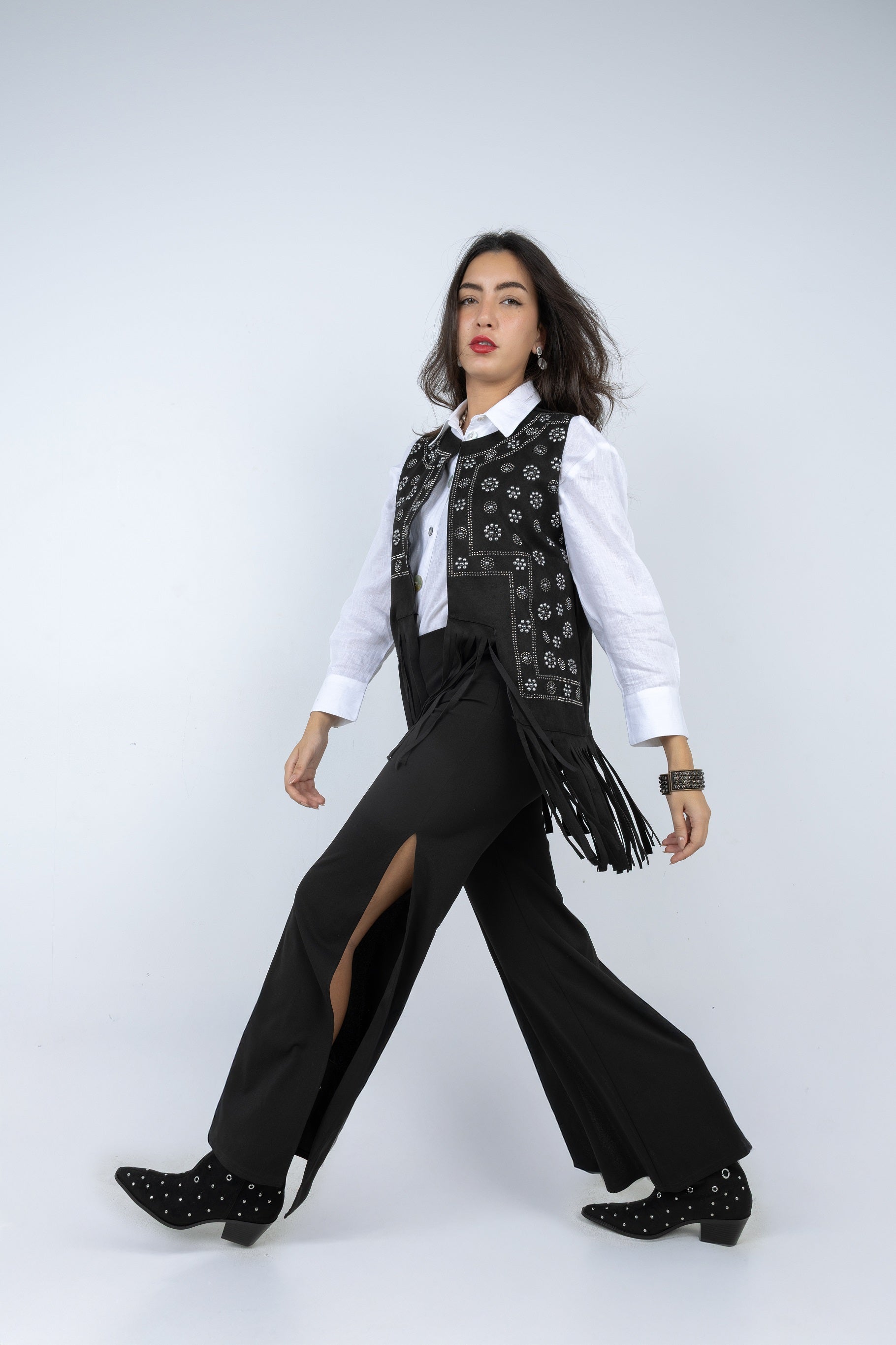 Woman wearing a black and white outfit with a patterned vest on a white background