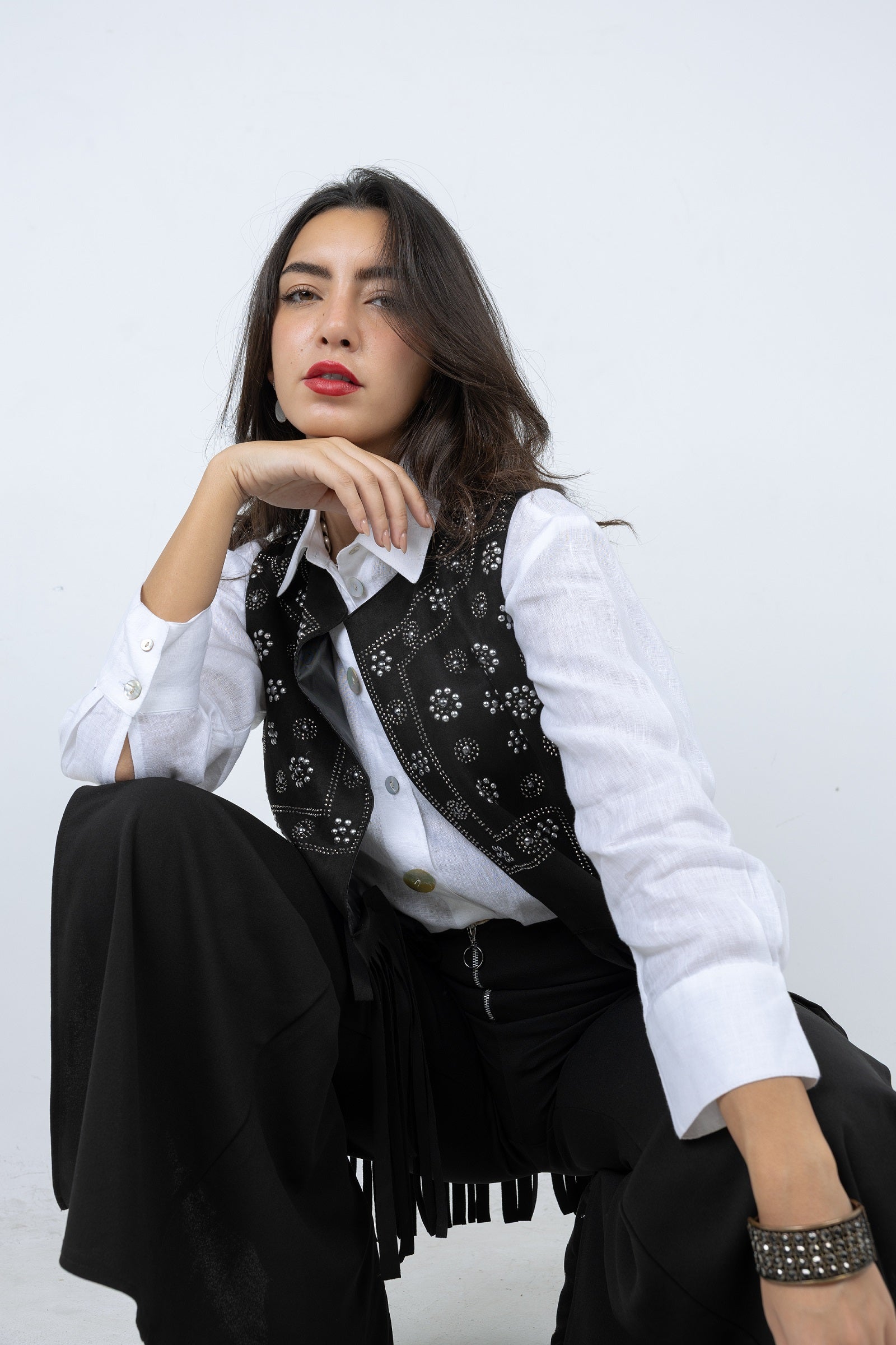 Woman wearing a white shirt, black vest, and black pants against a white background