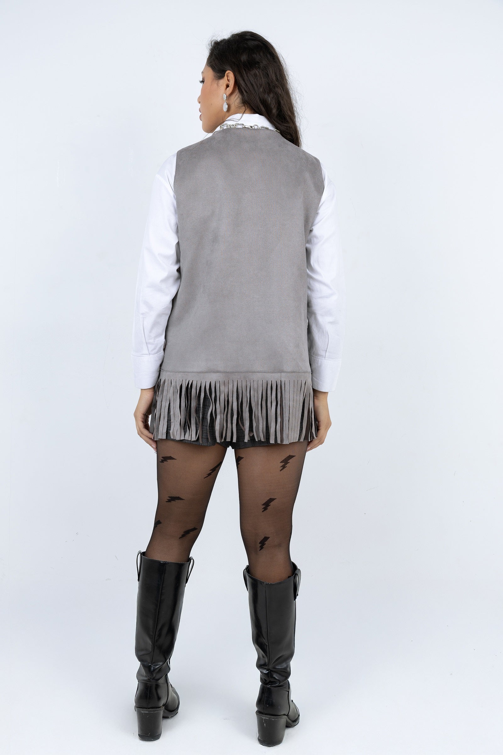 Person wearing a gray vest, white shirt, black skirt, and black knee-high boots on a white background