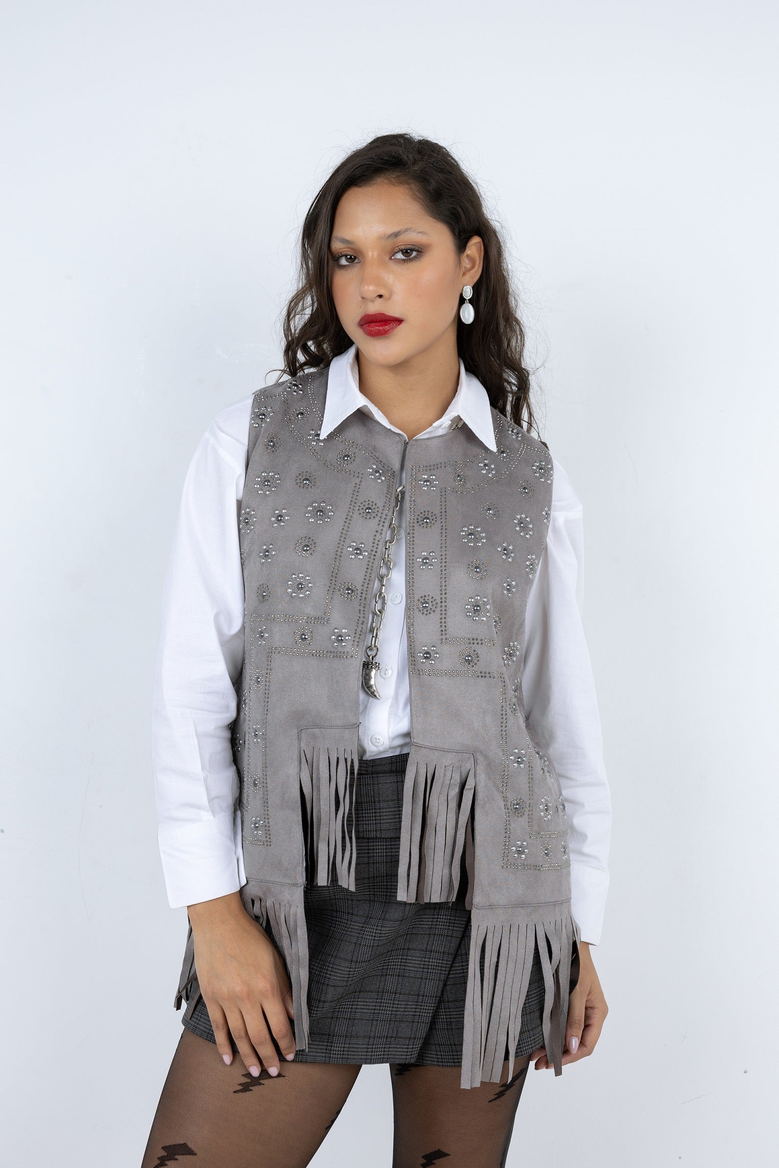Woman wearing a gray vest with fringe details on a white background