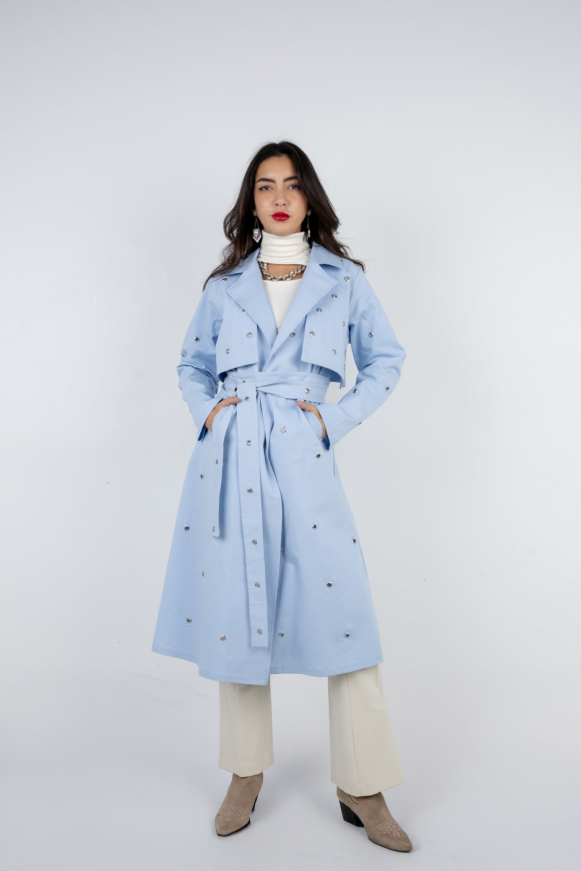 Woman wearing a light blue trench coat on a white background