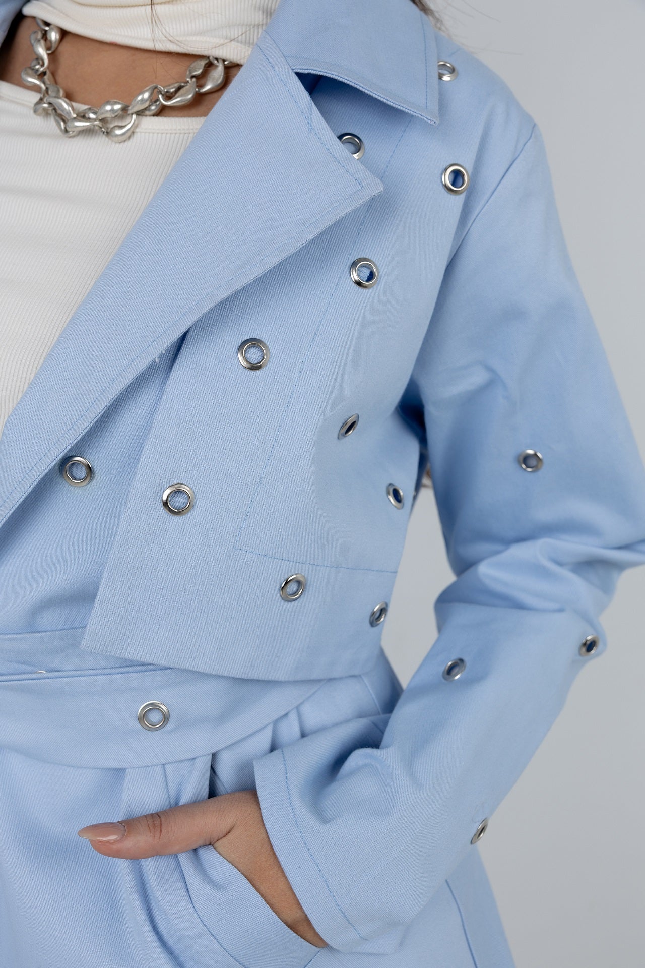 Light blue coat with silver buttons on a plain background