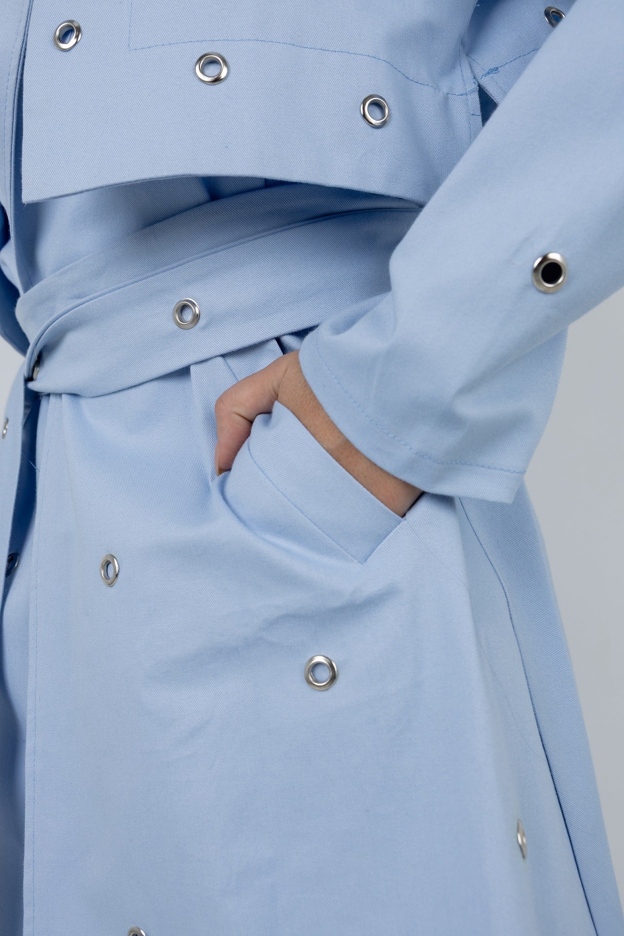 Light blue coat with button details on a plain background