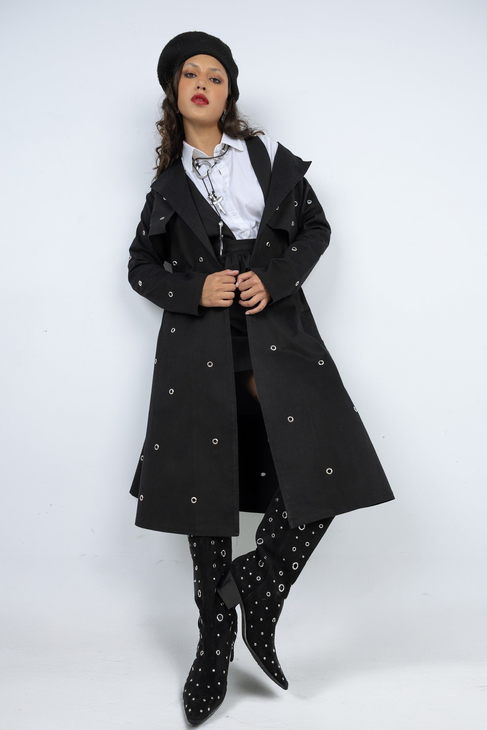 Woman wearing a black coat, hat, and boots on a white background