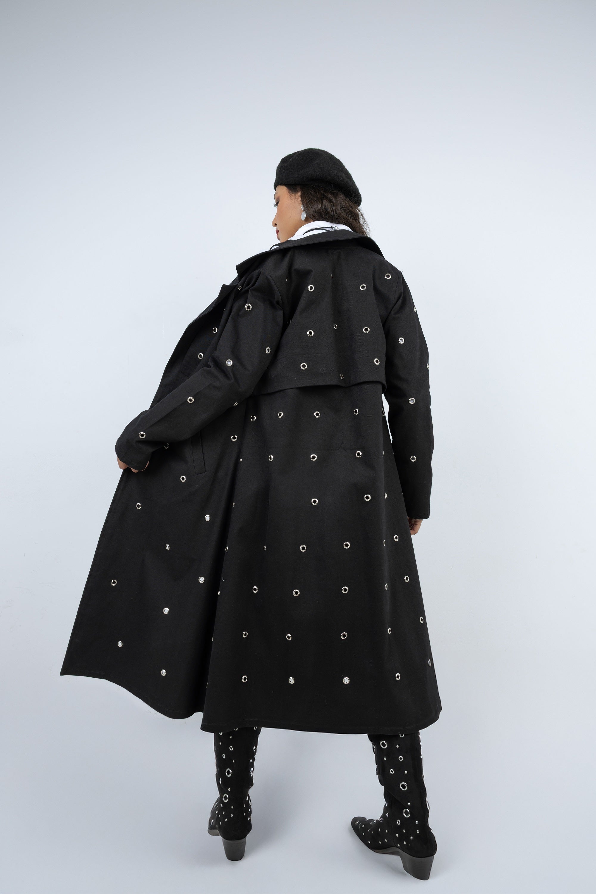 Person wearing a long black coat with white patterns on a white background
