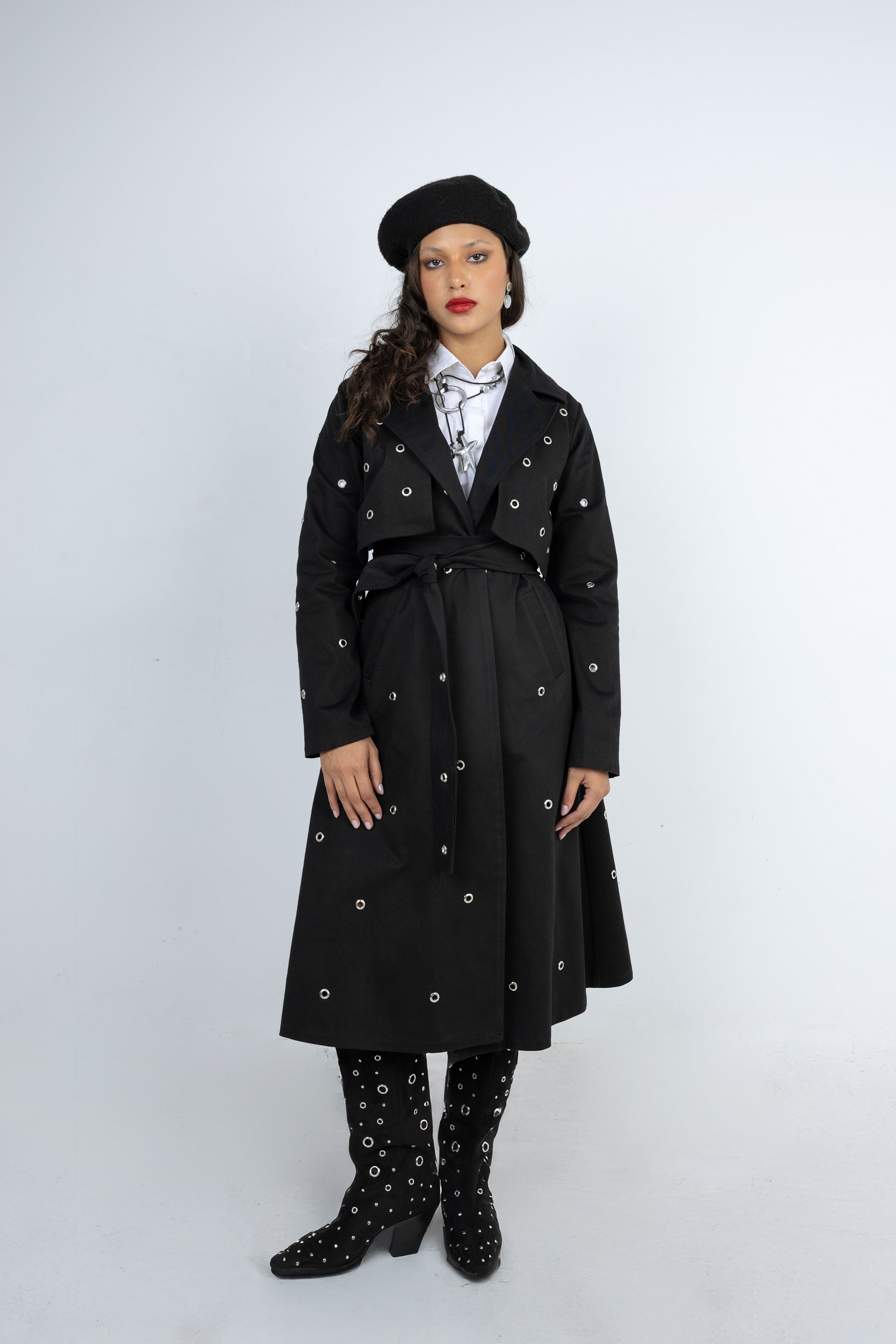 Person wearing a black coat, beret, and patterned shoes on a white background