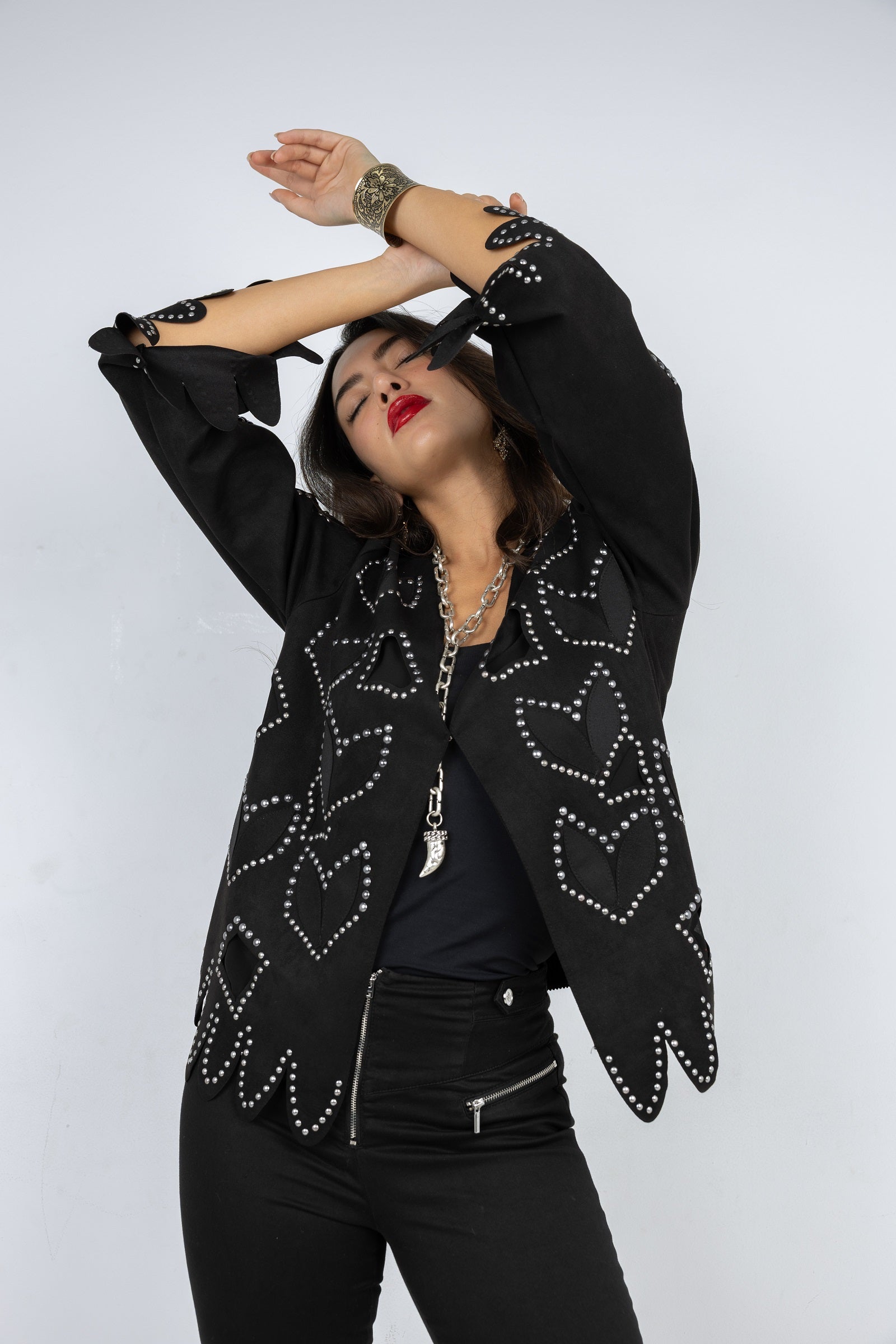 Person wearing a black studded jacket on a white background