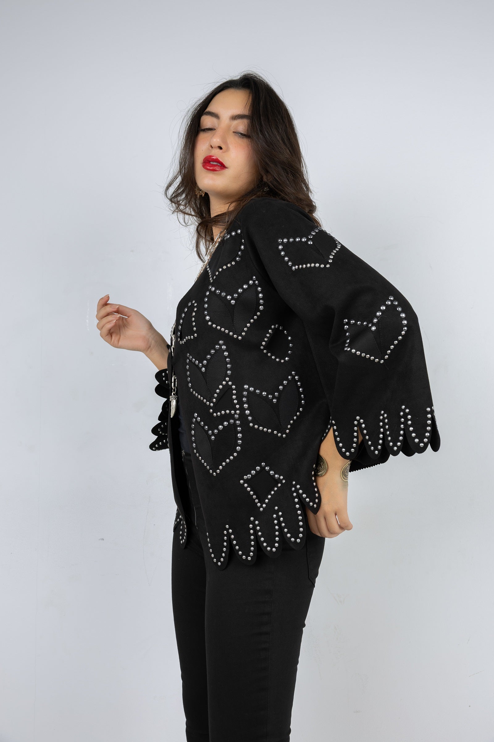 Woman wearing a black embellished jacket against a white background
