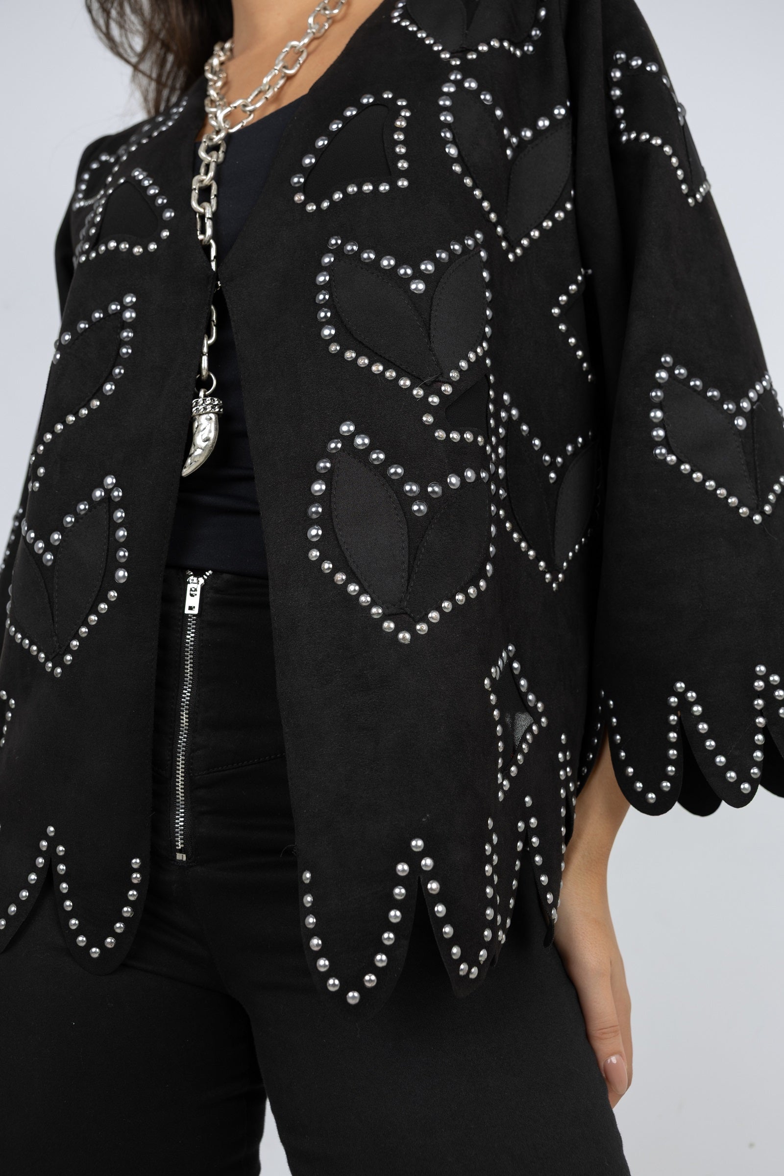 Black jacket with heart patterns and rhinestones on a plain background