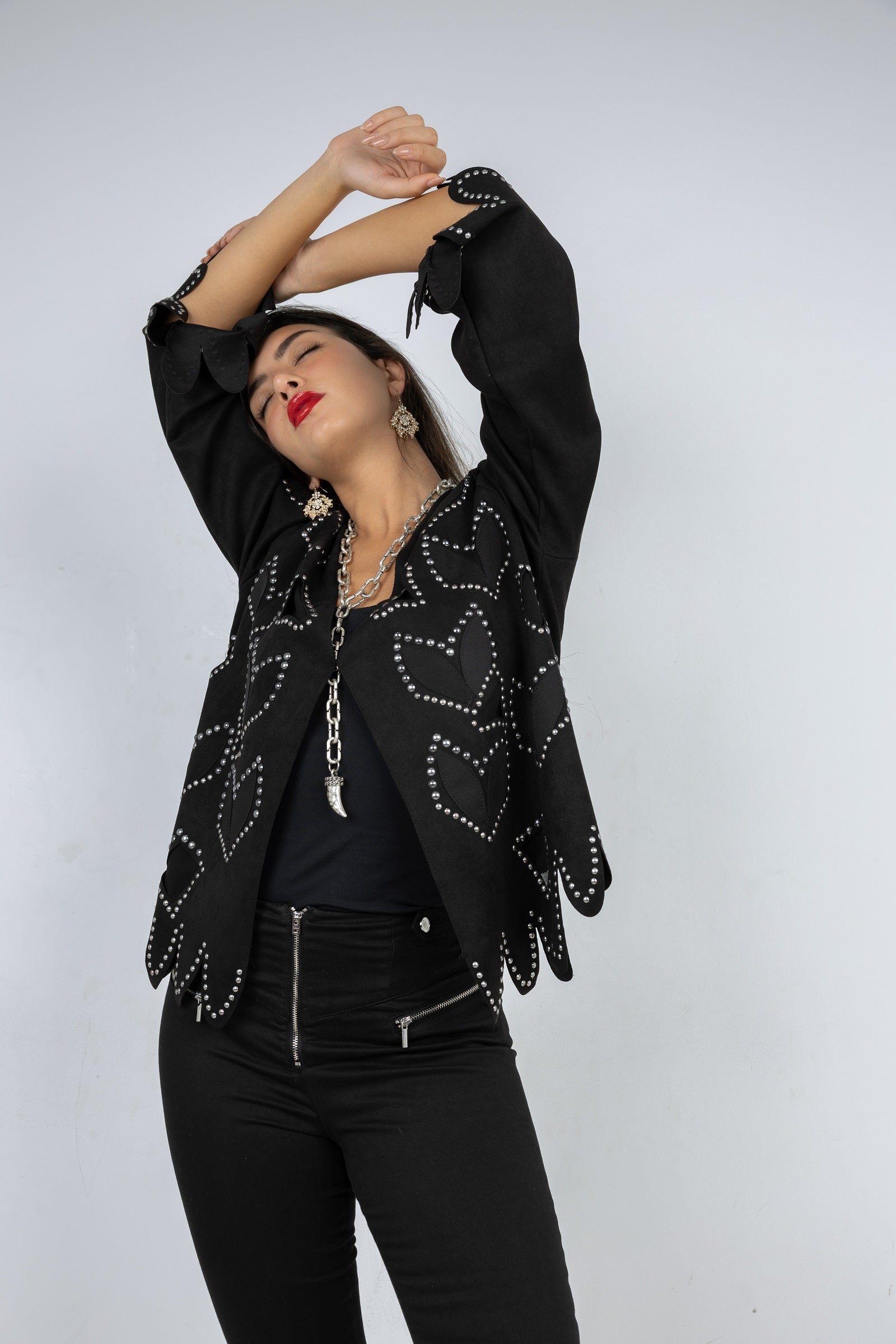 Person wearing a black embellished jacket on a white background
