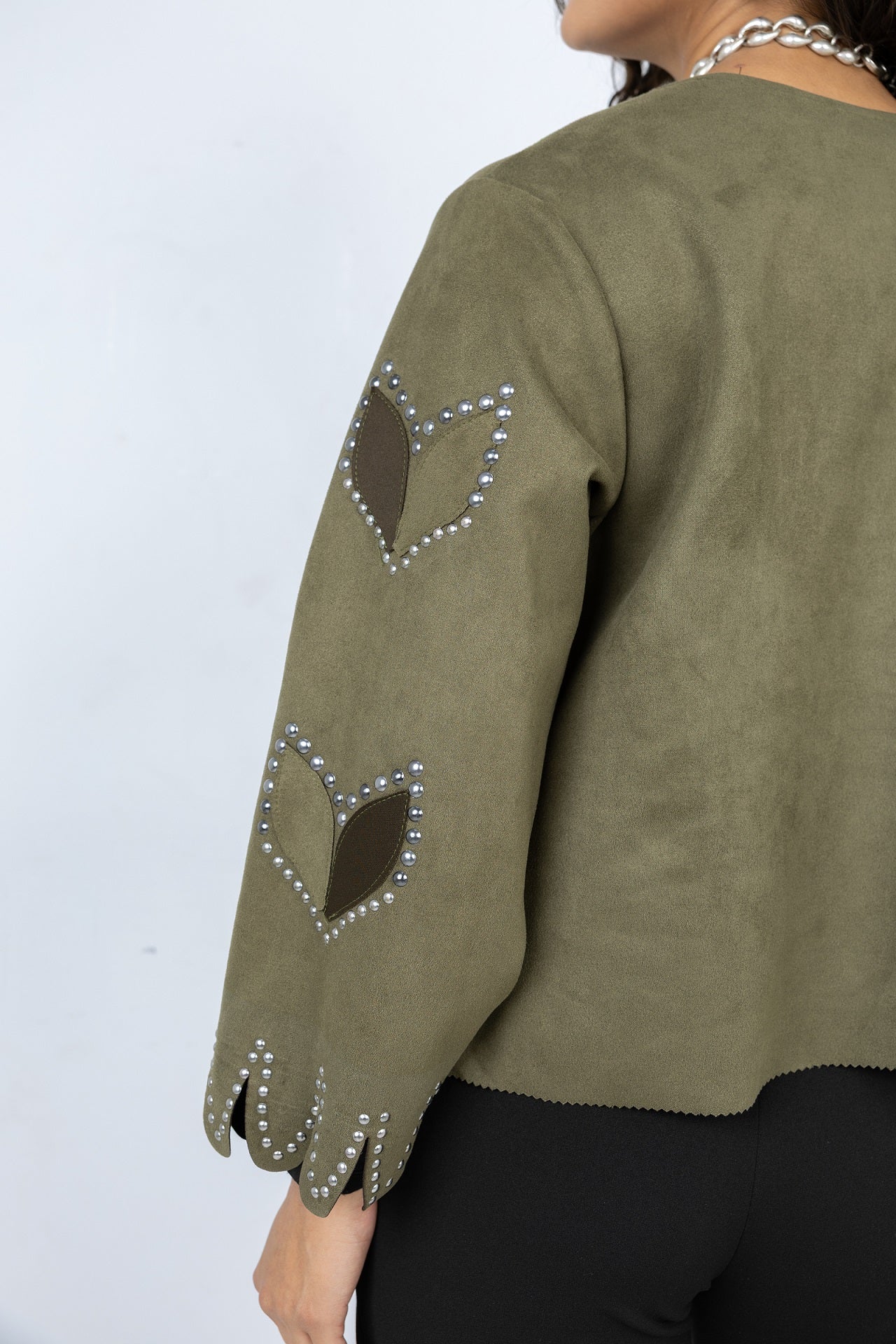 Green jacket with heart patterns and rhinestones on a plain background