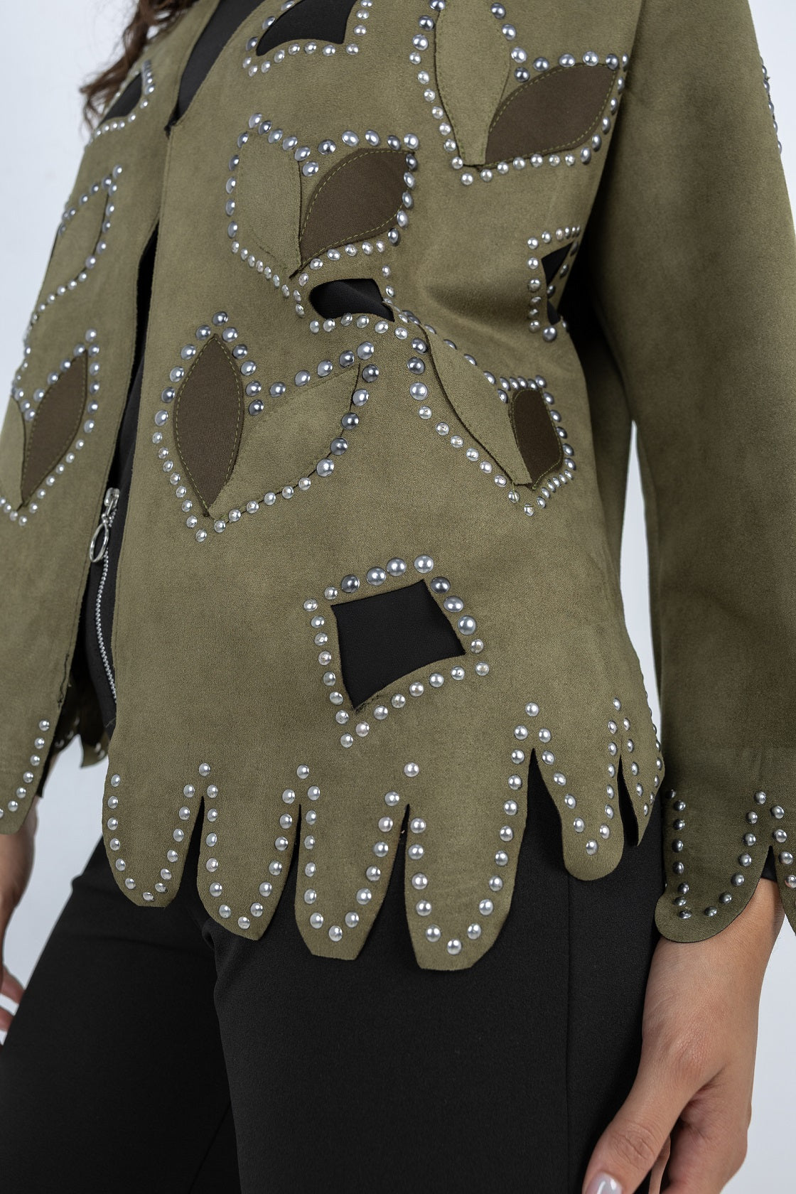 Green jacket with decorative cut-out patterns and rhinestone embellishments on a white background