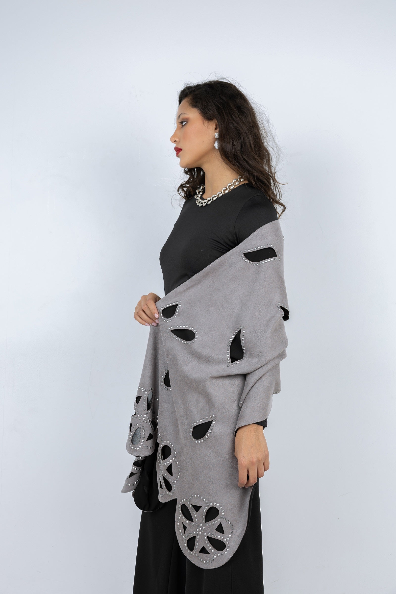 Woman wearing a gray patterned shawl over a black outfit on a white background