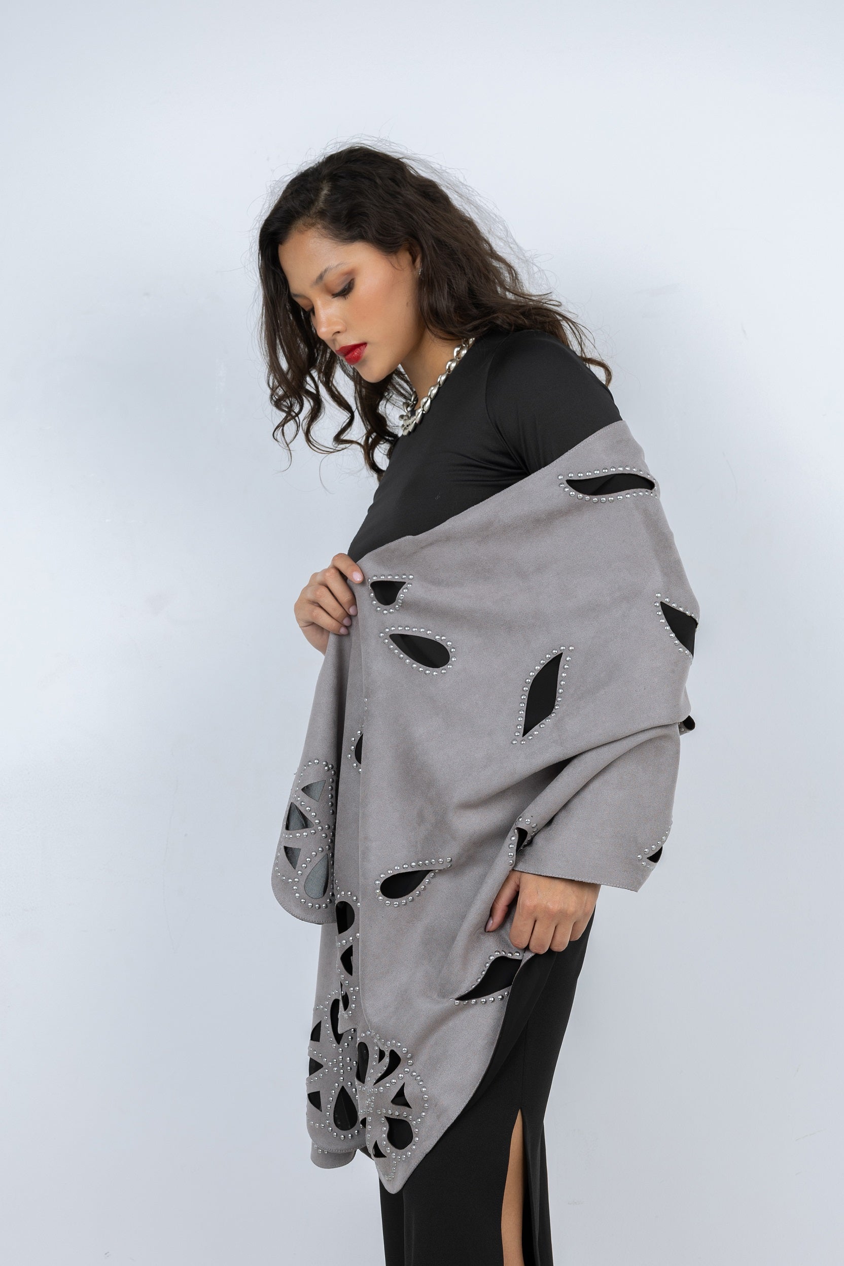 Woman holding a gray shawl with black leaf patterns against a white background