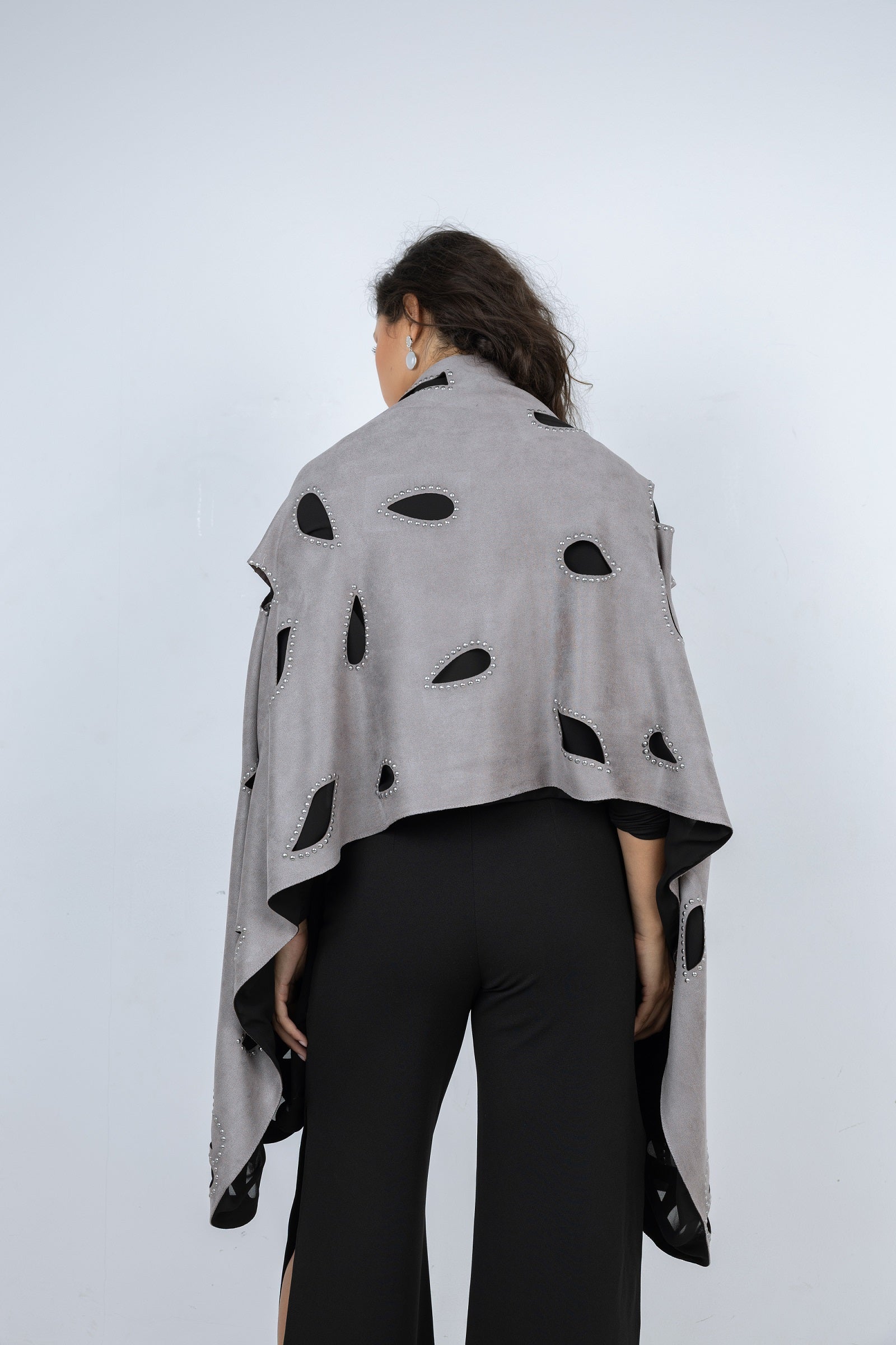 Person wearing a gray poncho with black polka dots on a white background