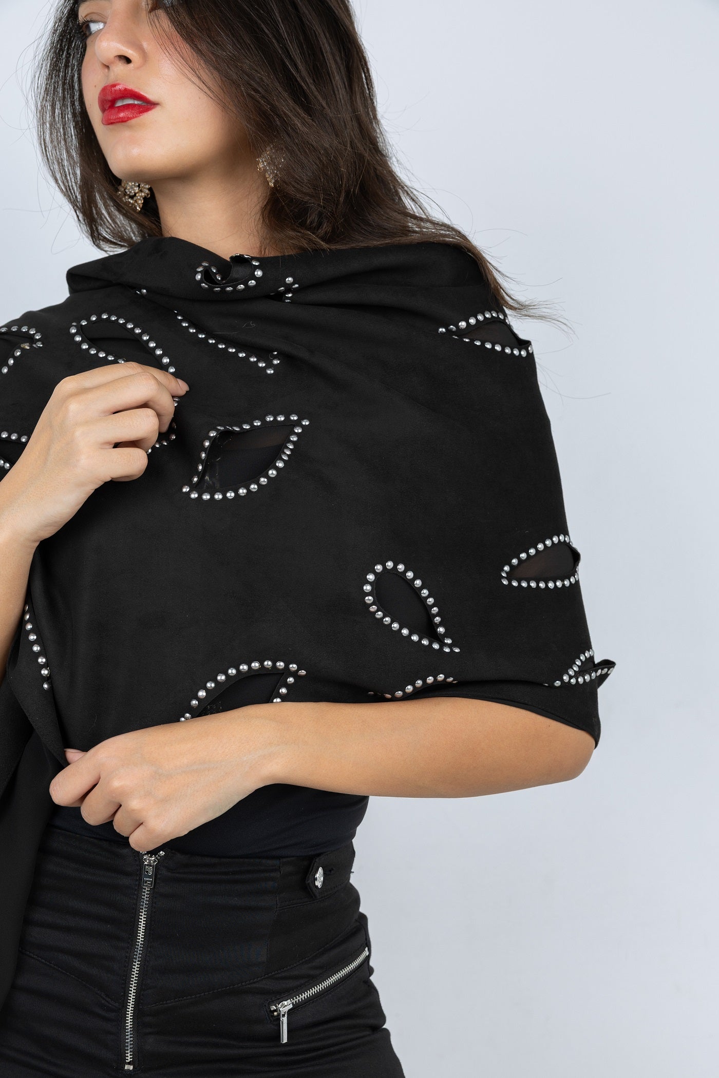 Black shawl with white patterns worn by a person on a light gray background