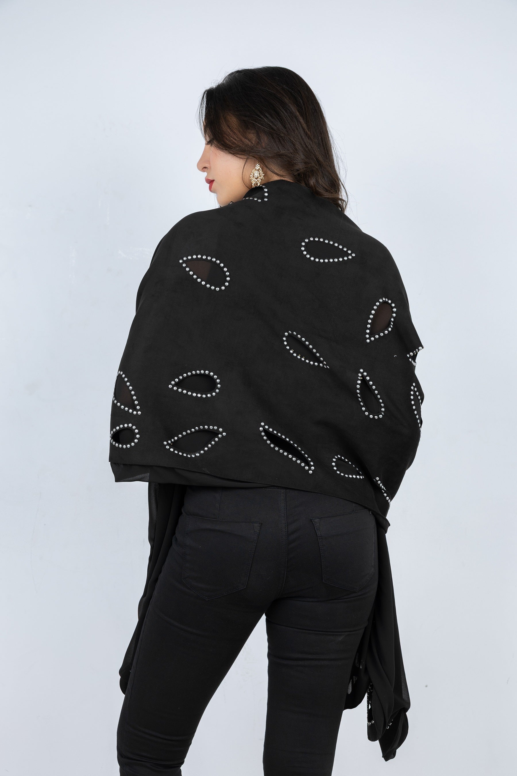 Person wearing a black shawl with white patterns on a white background