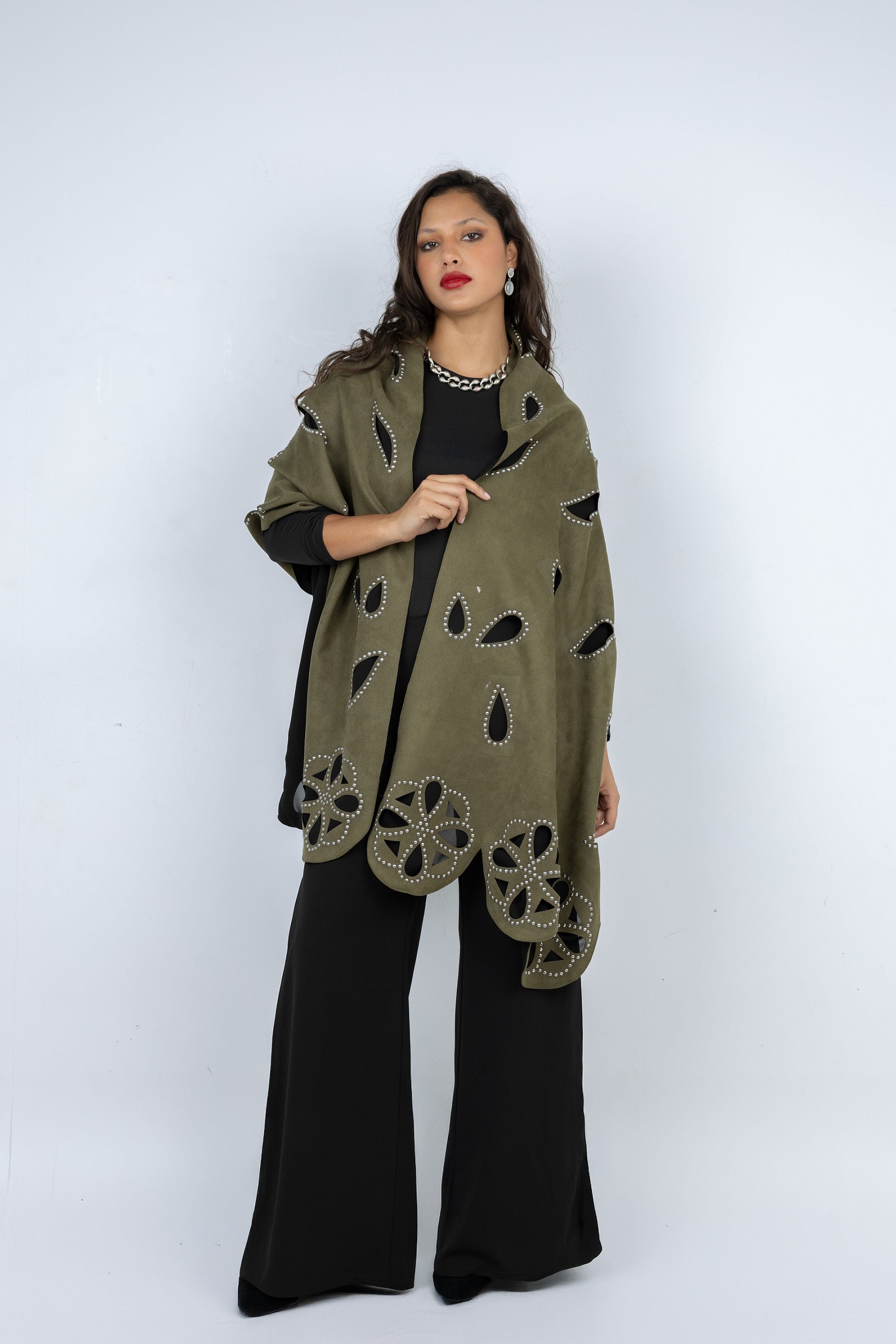 Woman wearing a green patterned shawl over a black outfit on a white background