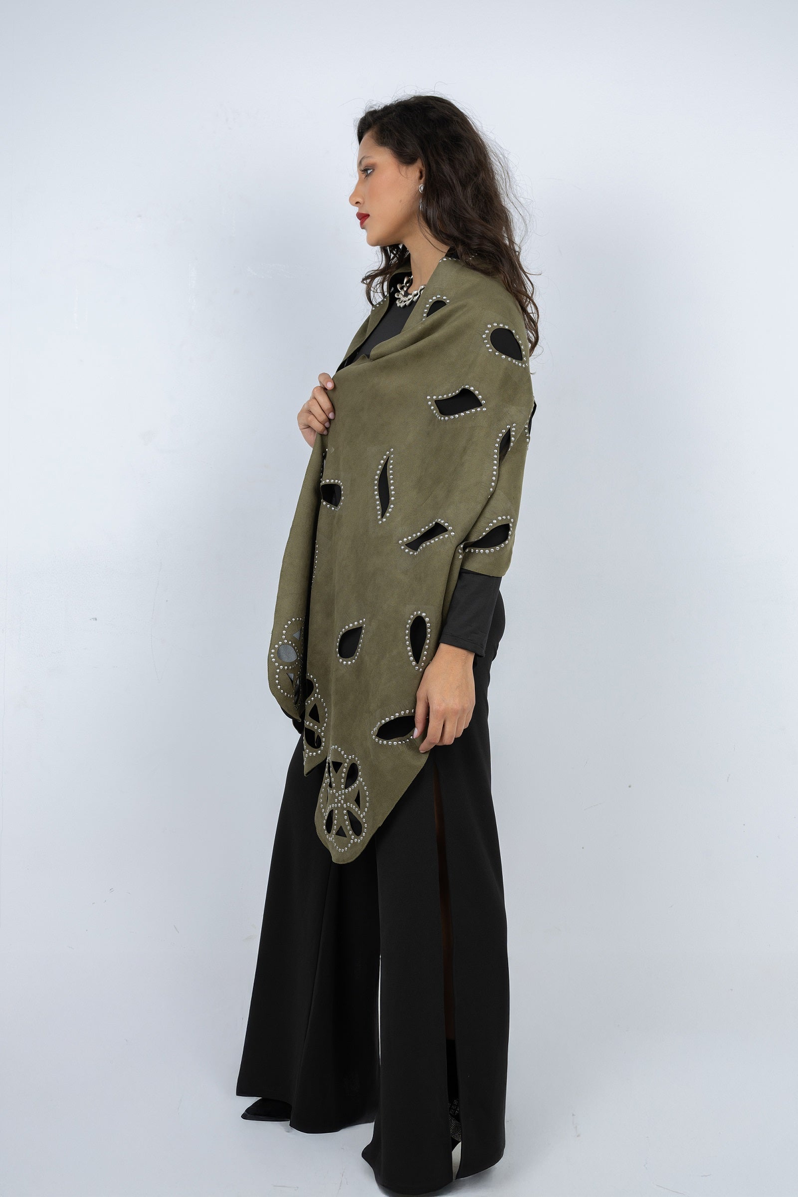 Woman wearing a green poncho with cut-out patterns on a white background