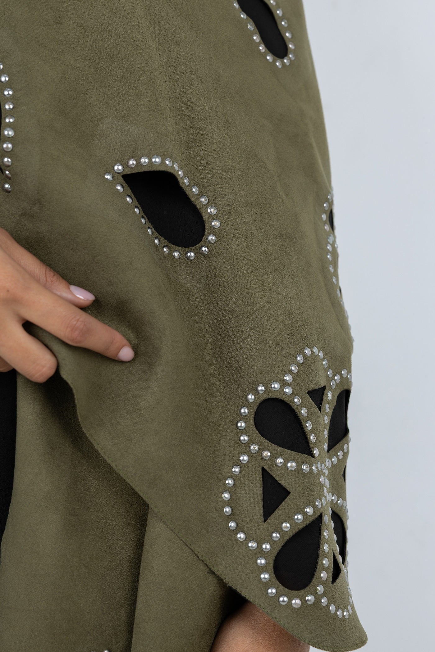 Green fabric with cut-out patterns and embellishments on a plain background