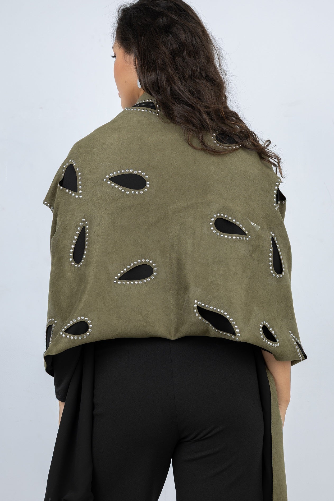 Woman wearing an olive green jacket with black cut-out patterns on a white background