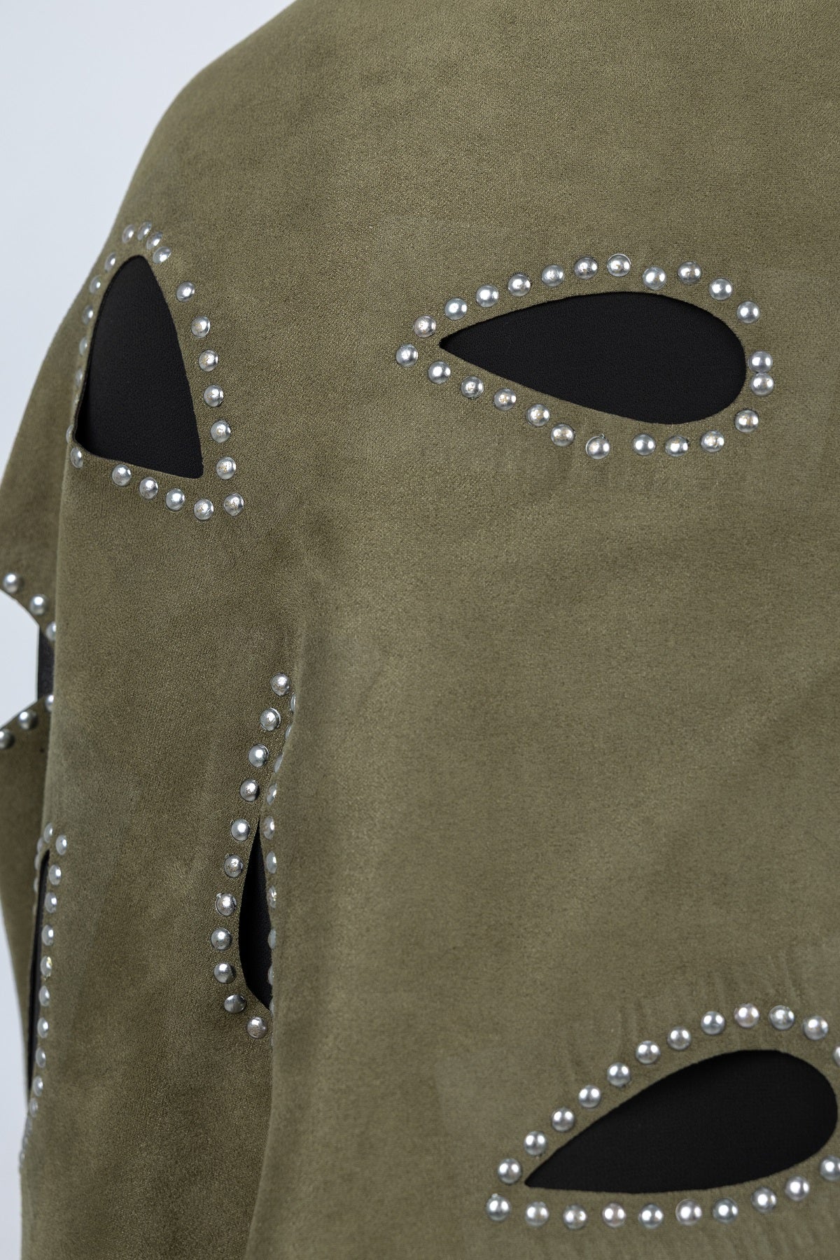 Green suede jacket with cut-out design and pearl embellishments on a light gray background