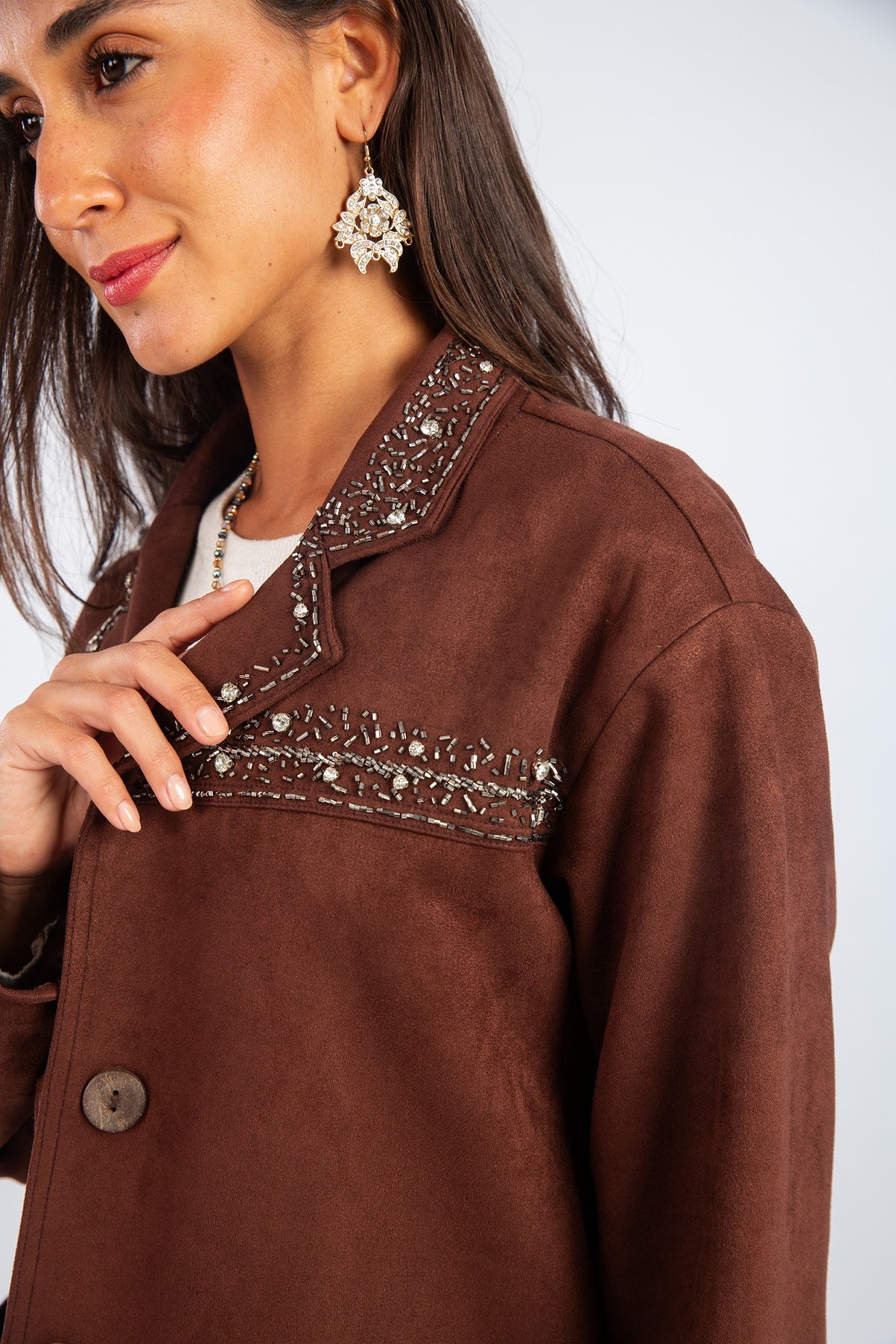Woman wearing a brown jacket with decorative trim on a white background