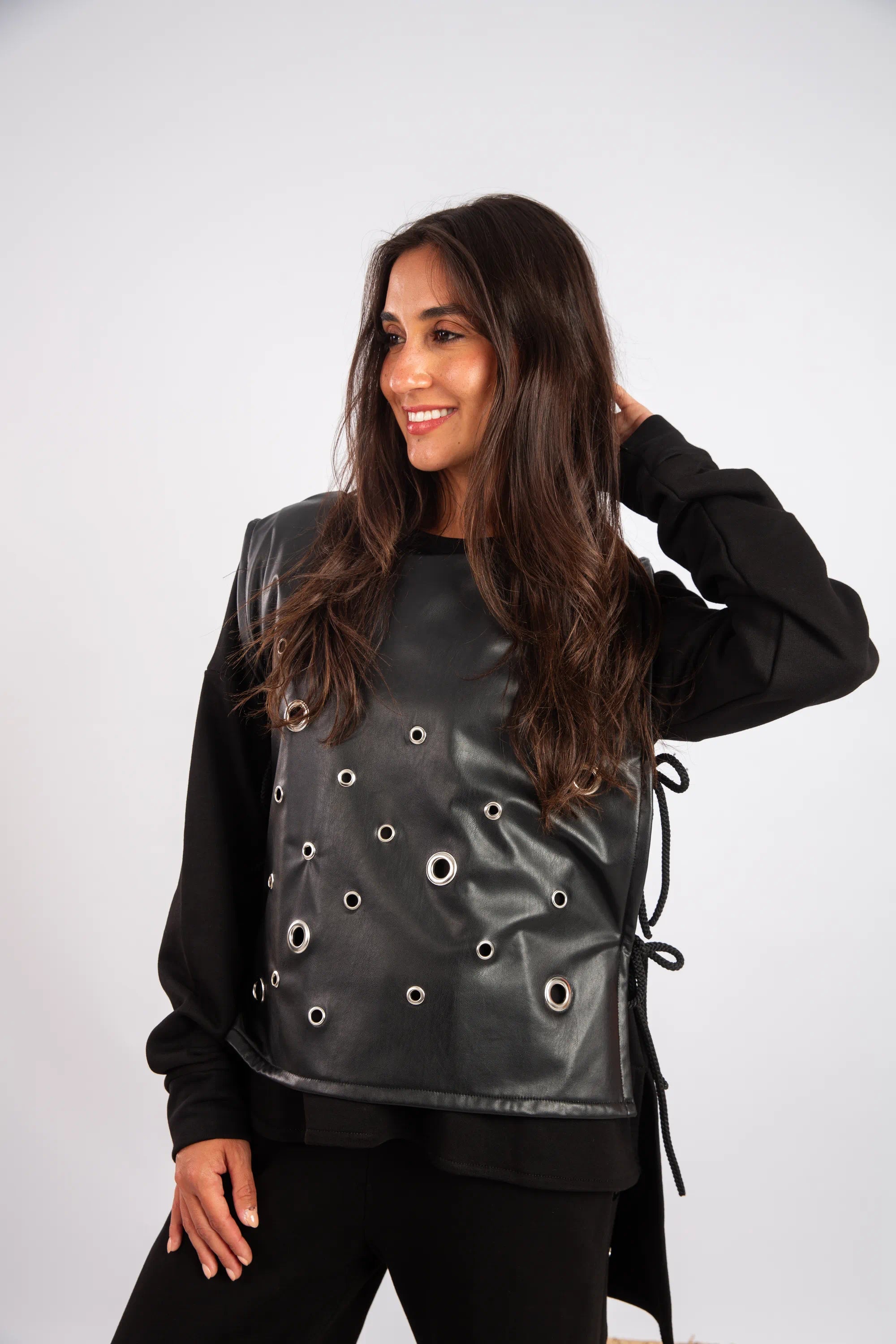Woman wearing a black leather vest with eyelets on a white background