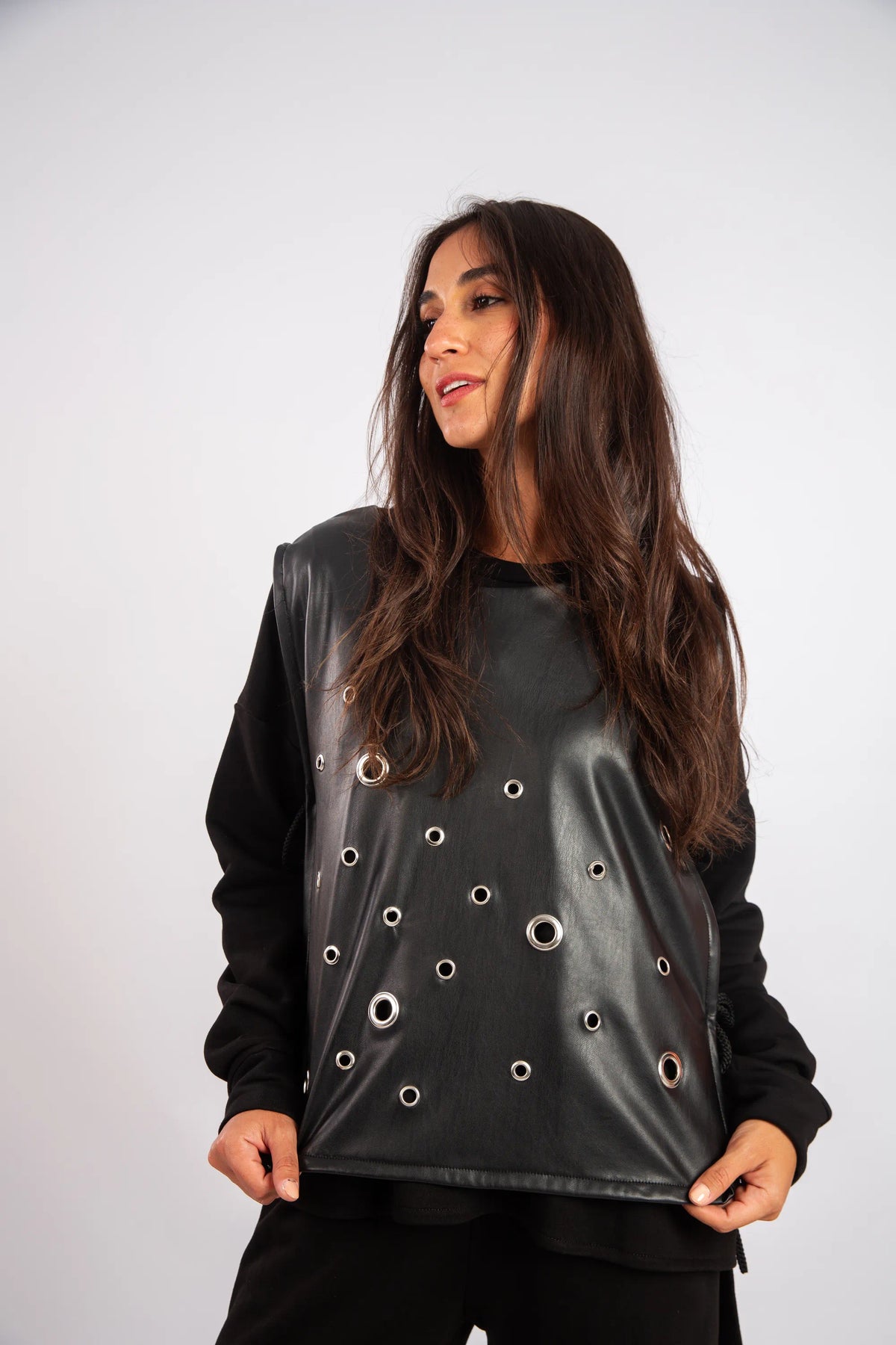 Woman wearing a black shiny top with circular cutouts on a white background