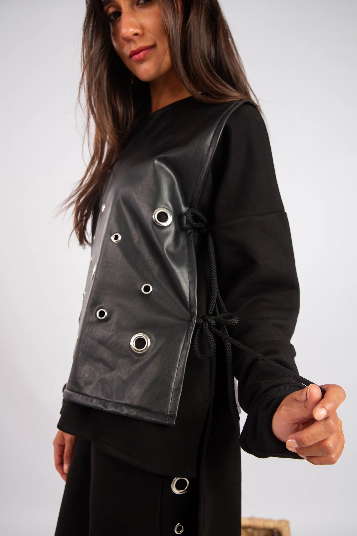 Woman wearing a black jacket with reflective panels on a plain background