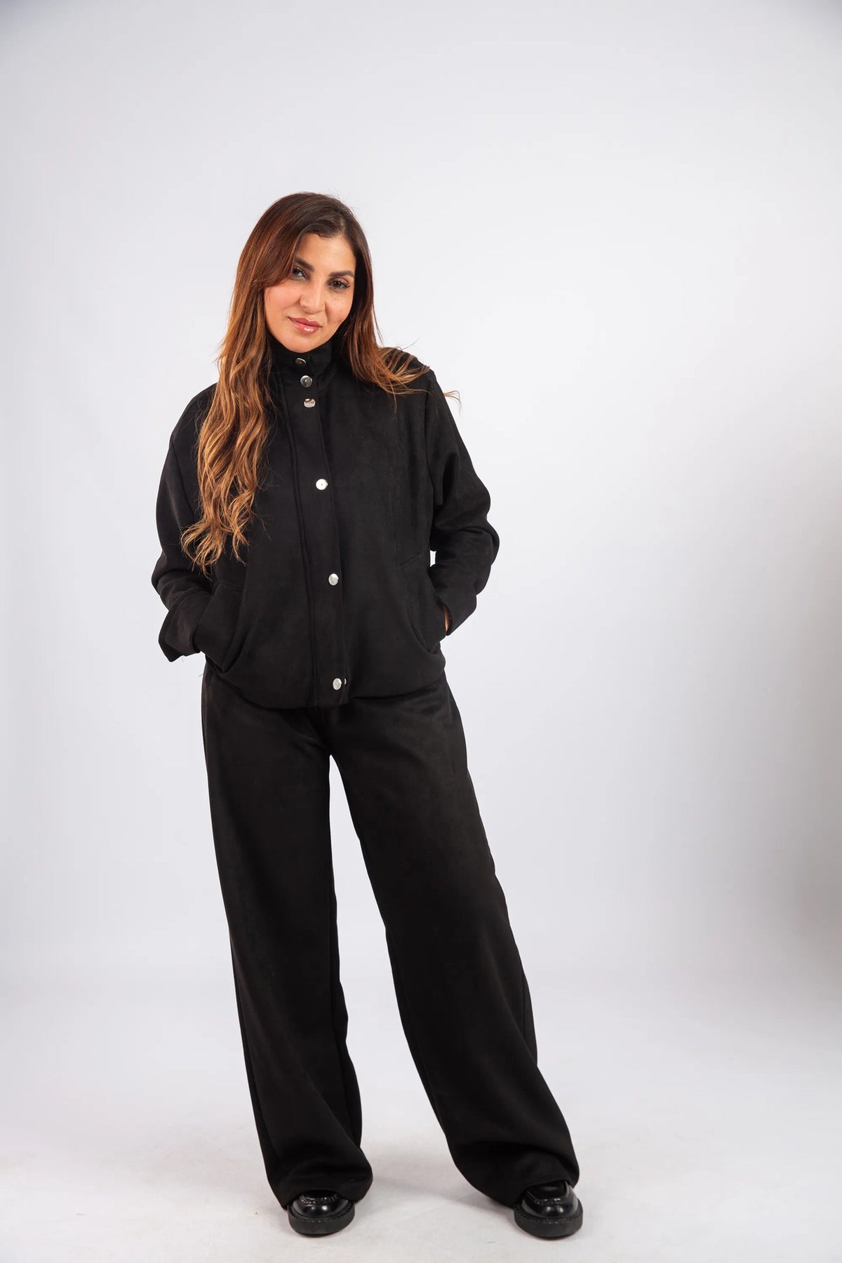 Woman wearing a black outfit with white buttons on a white background