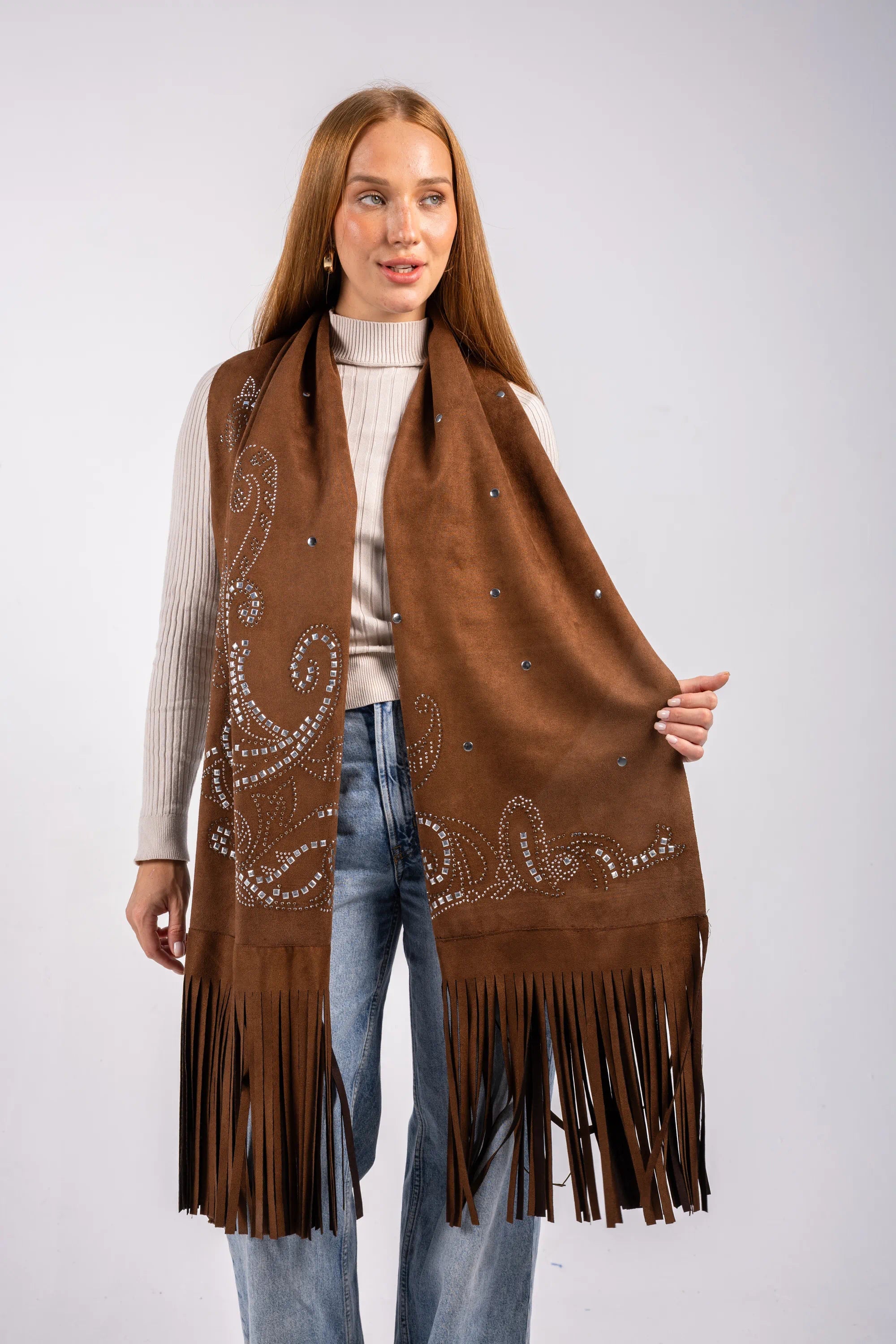 Woman wearing a brown fringe vest with intricate patterns on a plain background