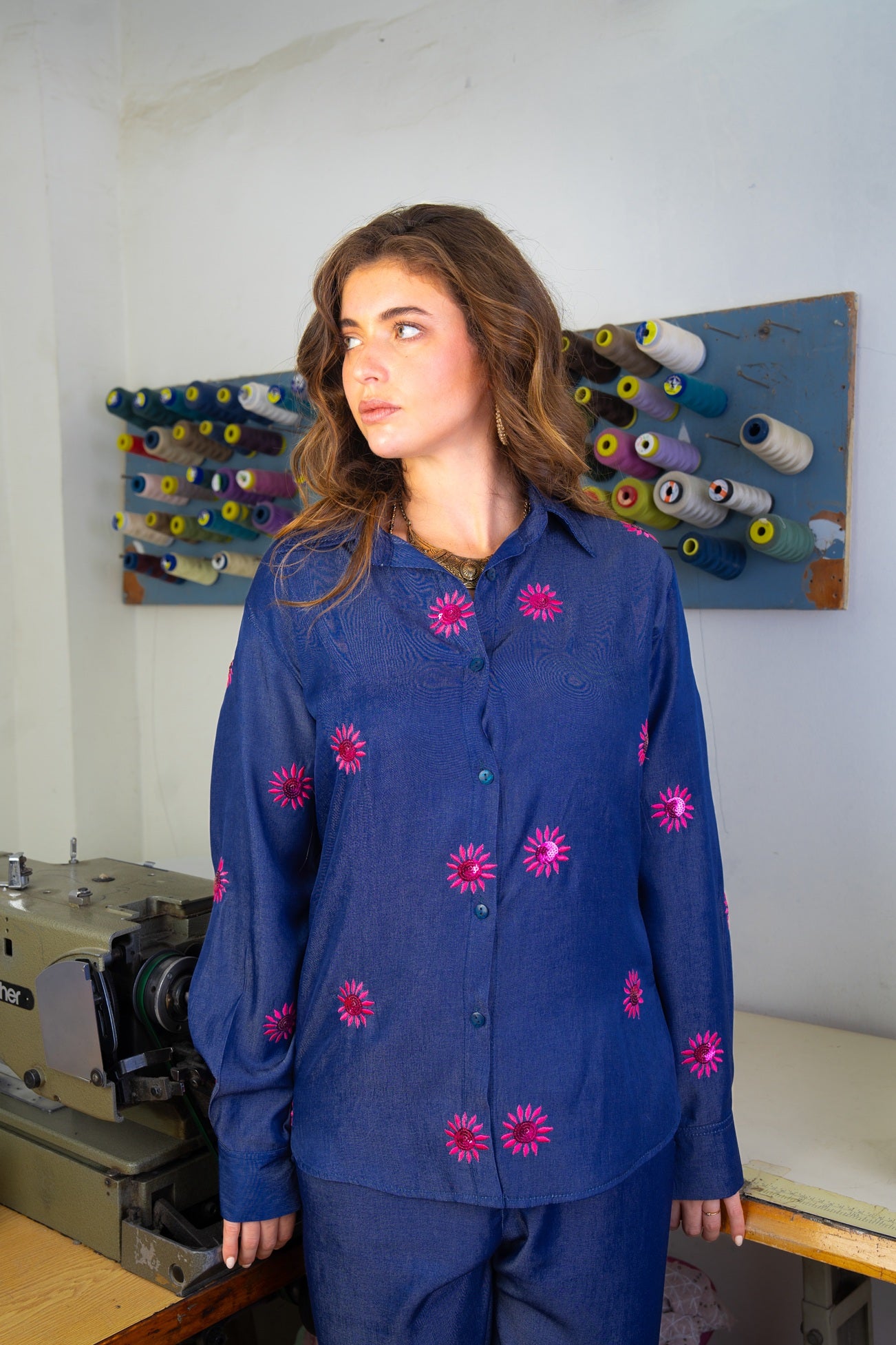 Woman wearing a blue outfit with pink floral patterns in a sewing room.