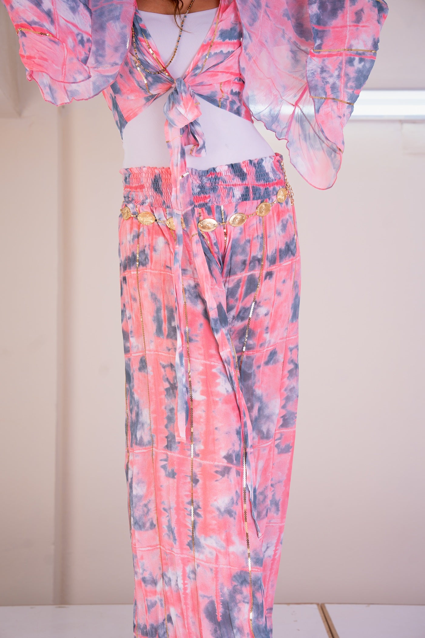 Person wearing a colorful outfit with a patterned top and pants against a neutral background