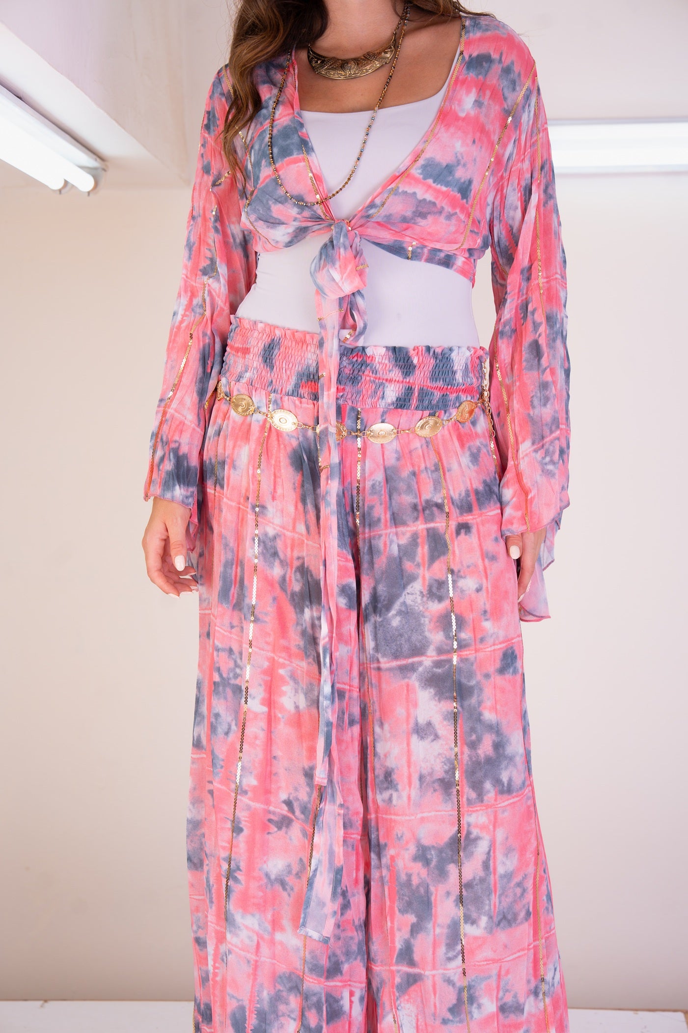 Person wearing a pink floral dress with a white top underneath on a plain background