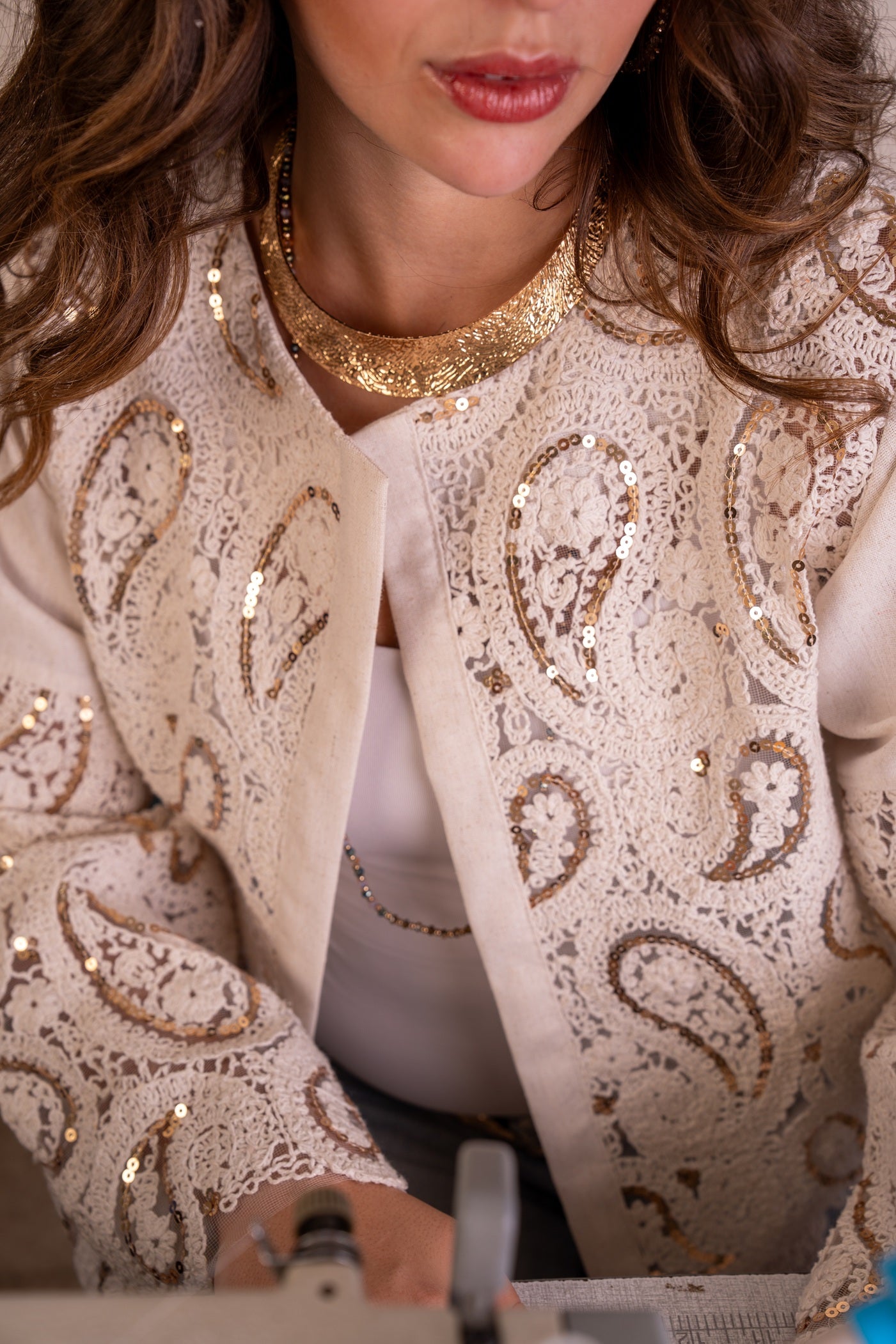 Close-up of a person wearing a beige sequined jacket with intricate patterns.