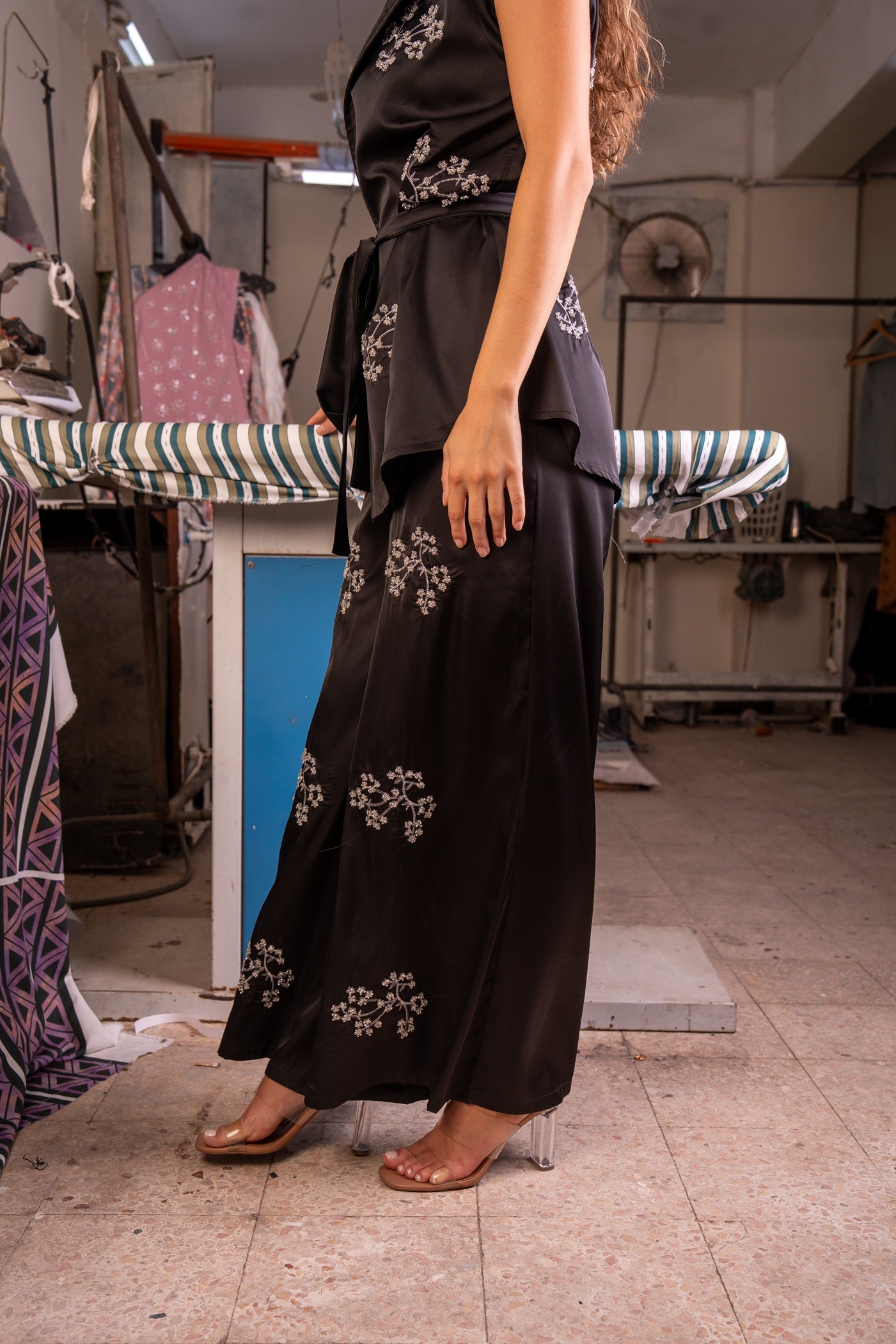 Person wearing a black dress with floral embroidery in an indoor setting