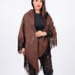 Woman wearing a brown patterned shawl with fringes on a white background