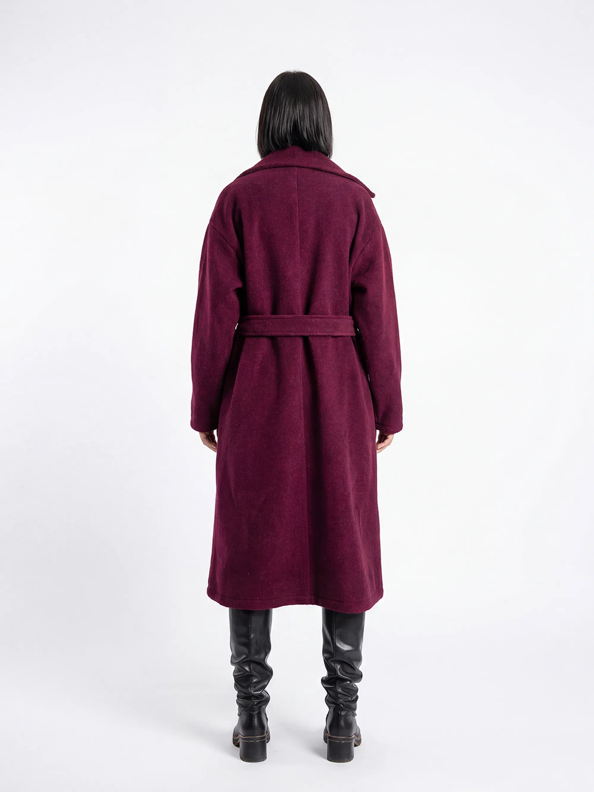 Person wearing a long burgundy coat on a white background