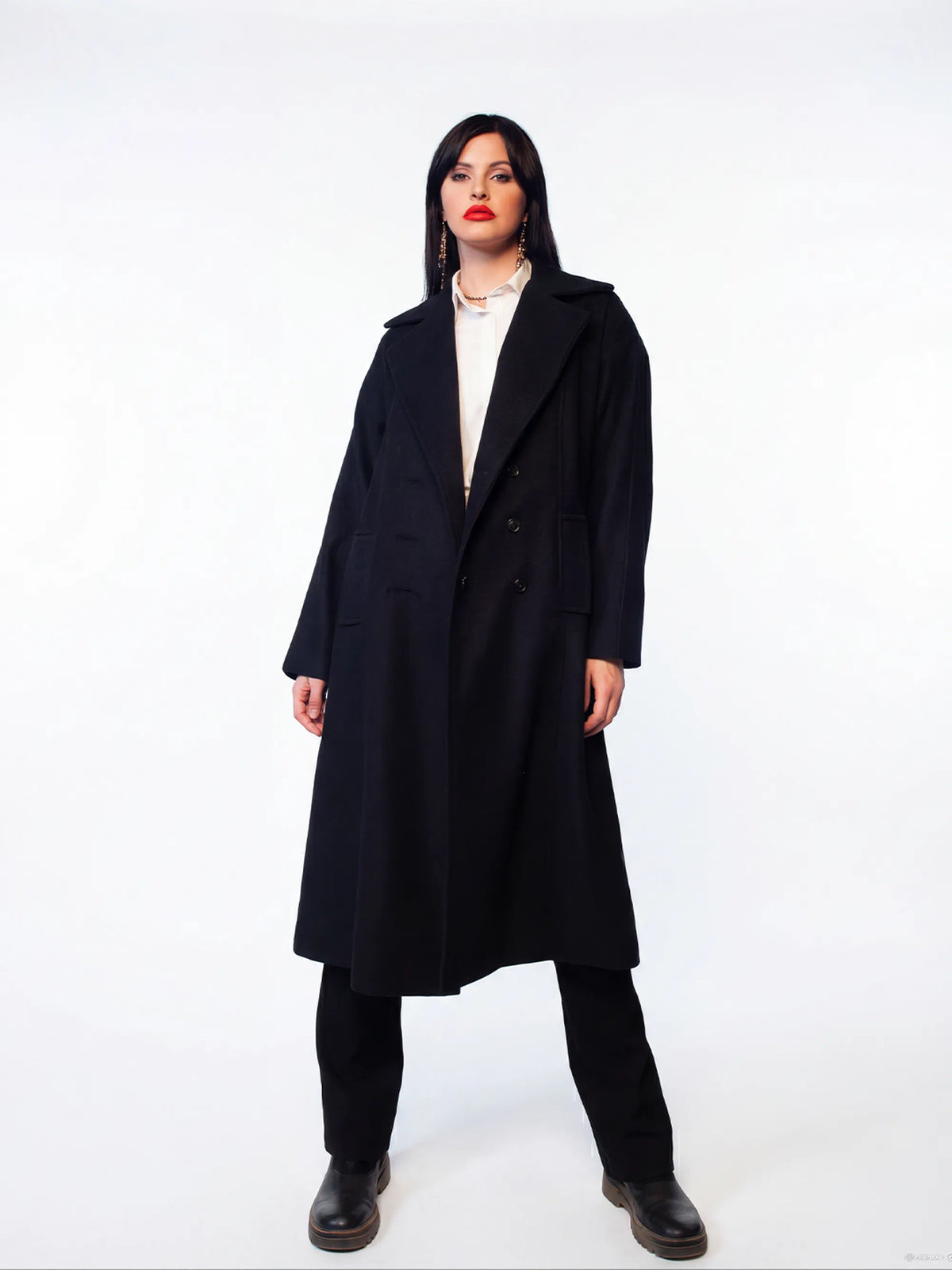 Person wearing a long black coat on a white background