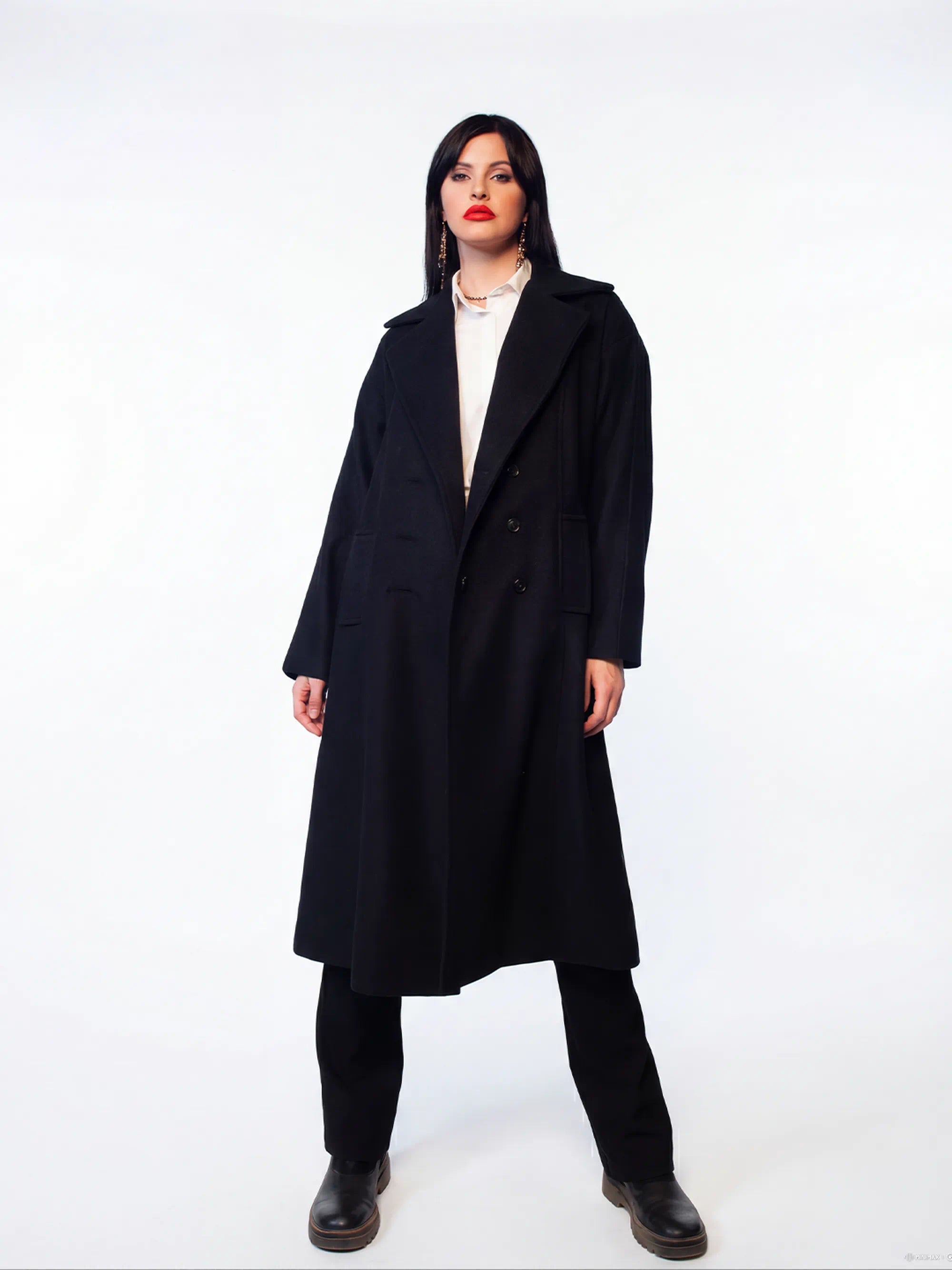 Person wearing a long black coat on a white background
