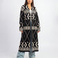 Woman wearing a long black and white patterned coat on a white background