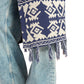 Navy blue and white patterned scarf with tassels draped over a denim jacket.