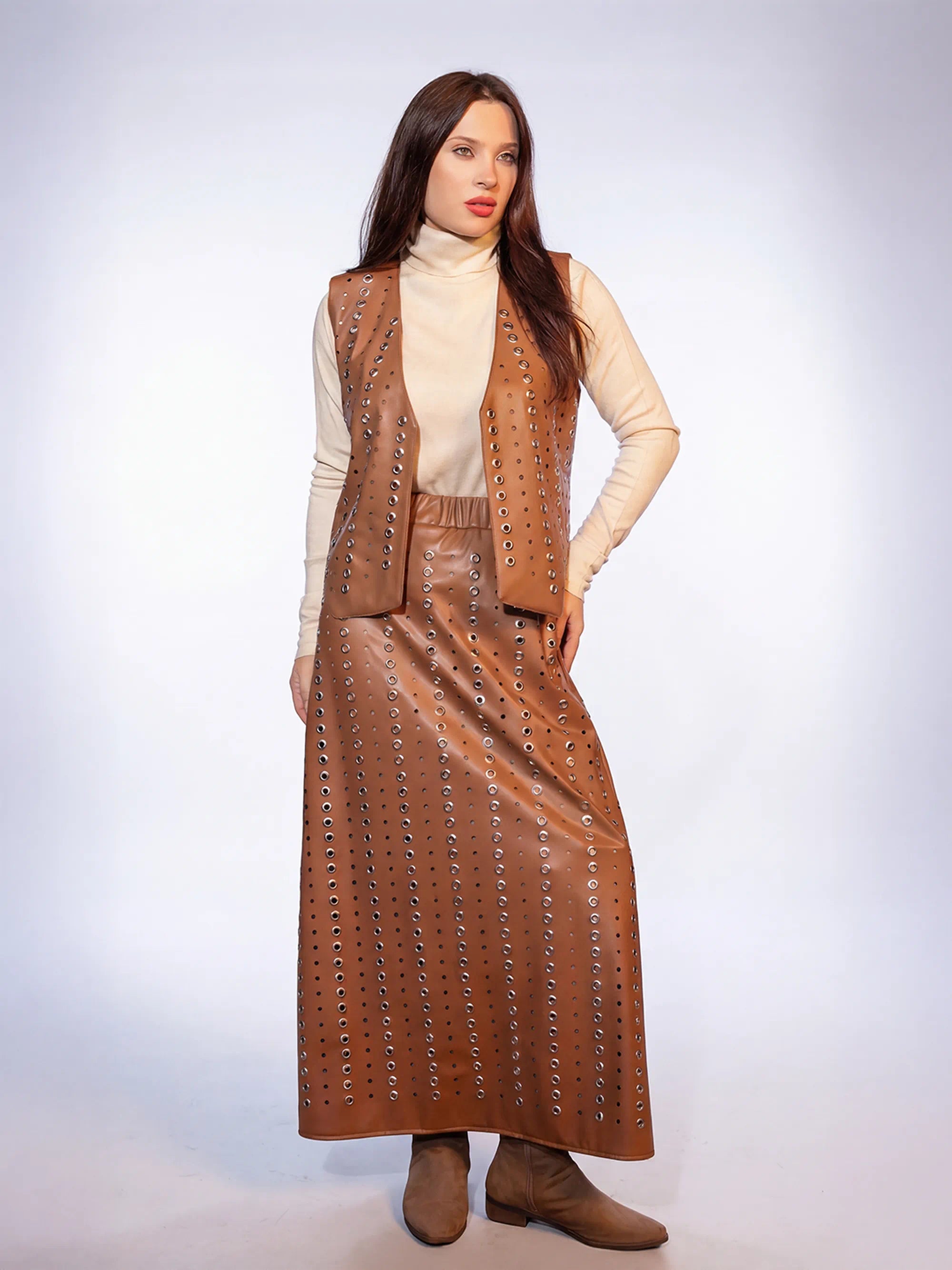 Woman wearing a brown leather outfit with a vest and skirt on a white background