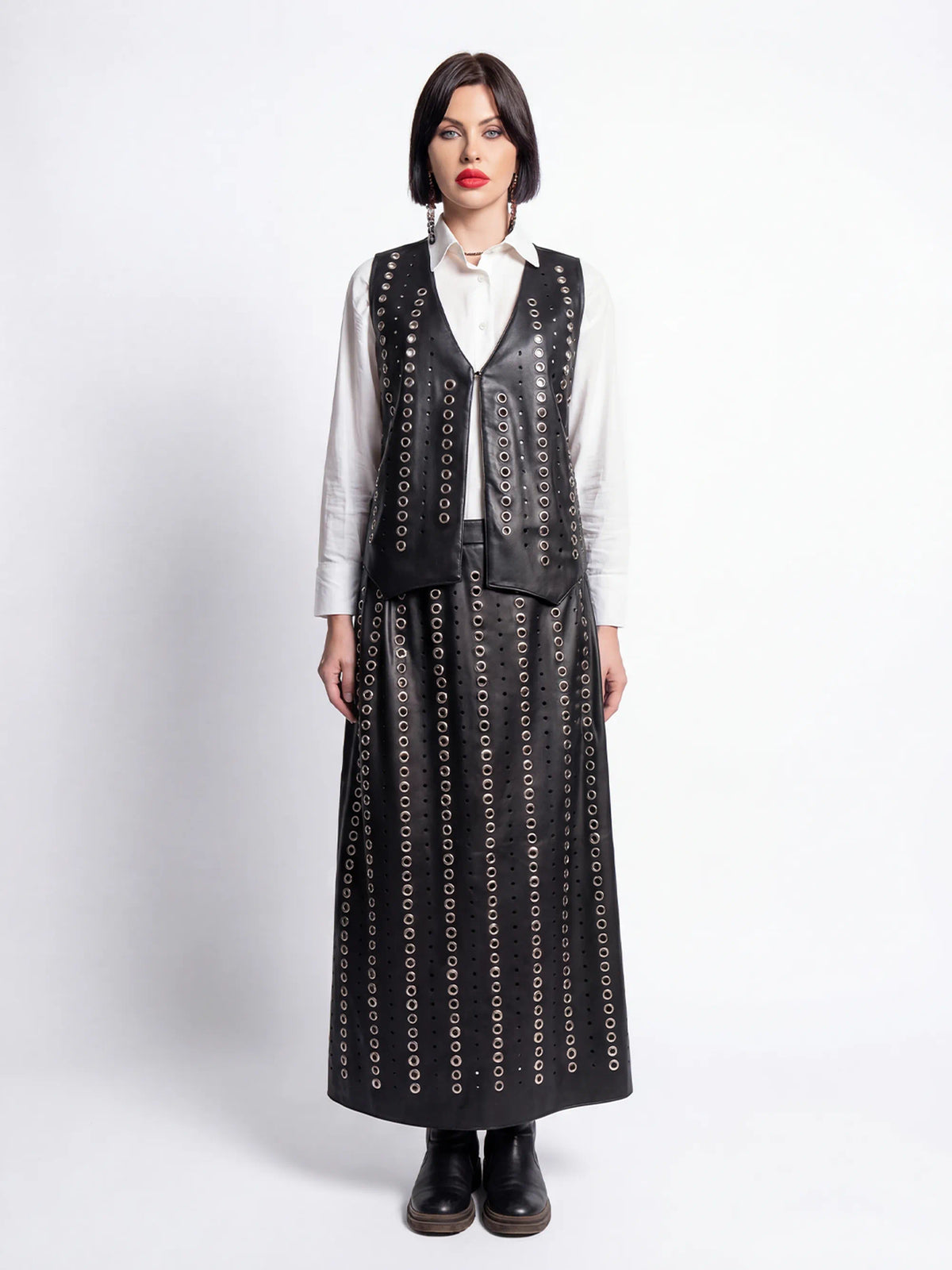 Woman wearing a long black patterned dress over a white shirt on a white background