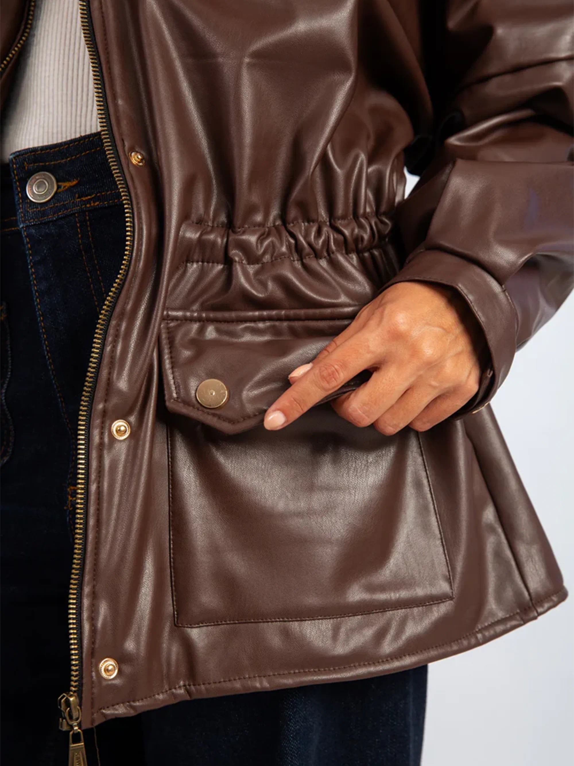 Close-up of a brown leather jacket with a hand reaching into a pocket.