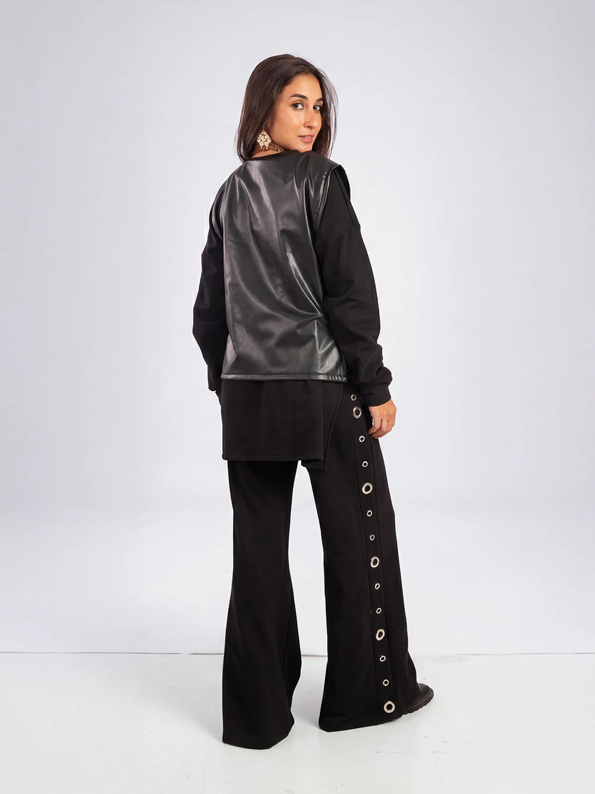 Woman wearing a black outfit with a metallic vest on a white background